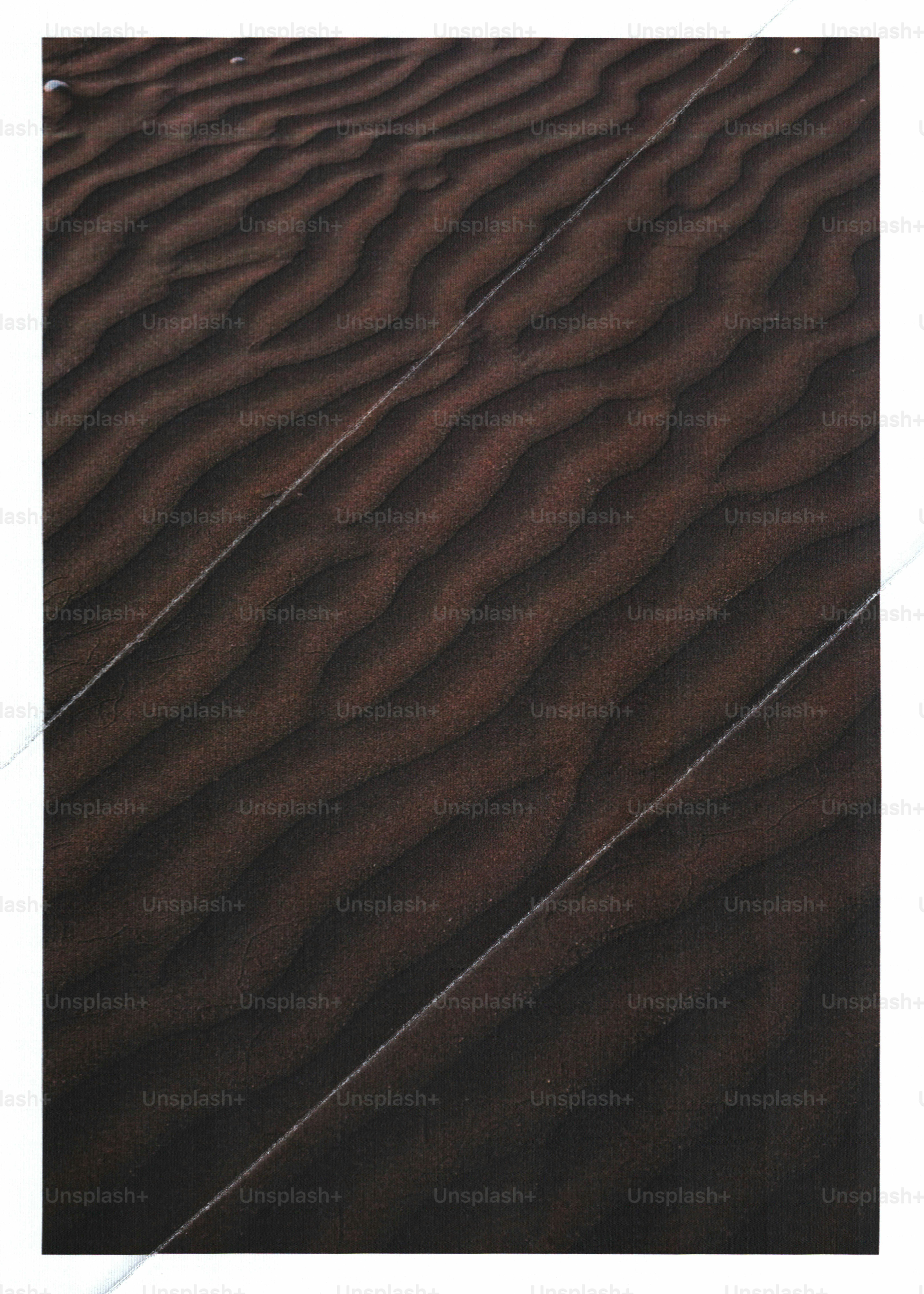 Dark brown sand dunes with rhythmic ripples and diagonal lines across the surface