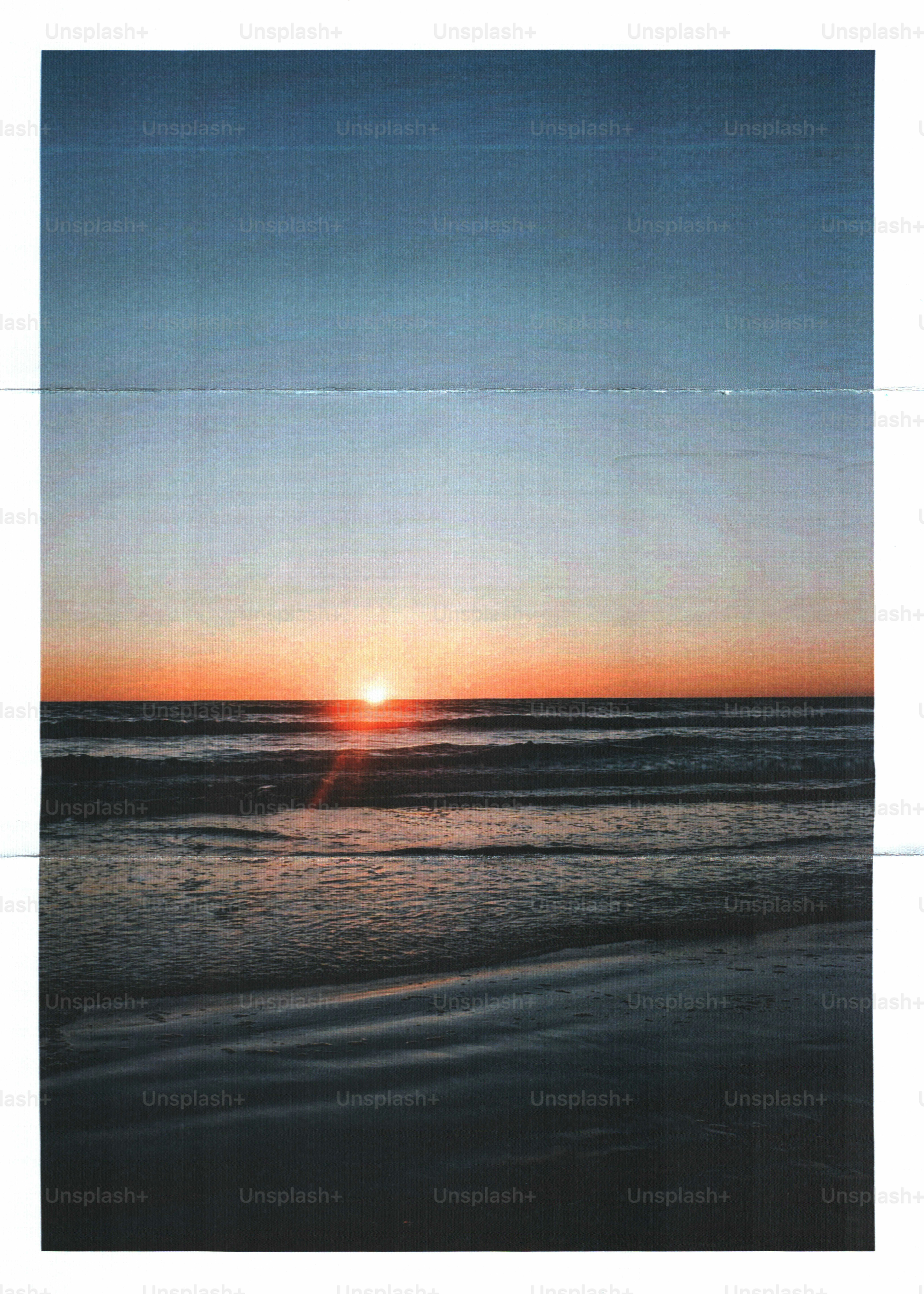 Low sun over a dark ocean with gentle waves on a sandy beach