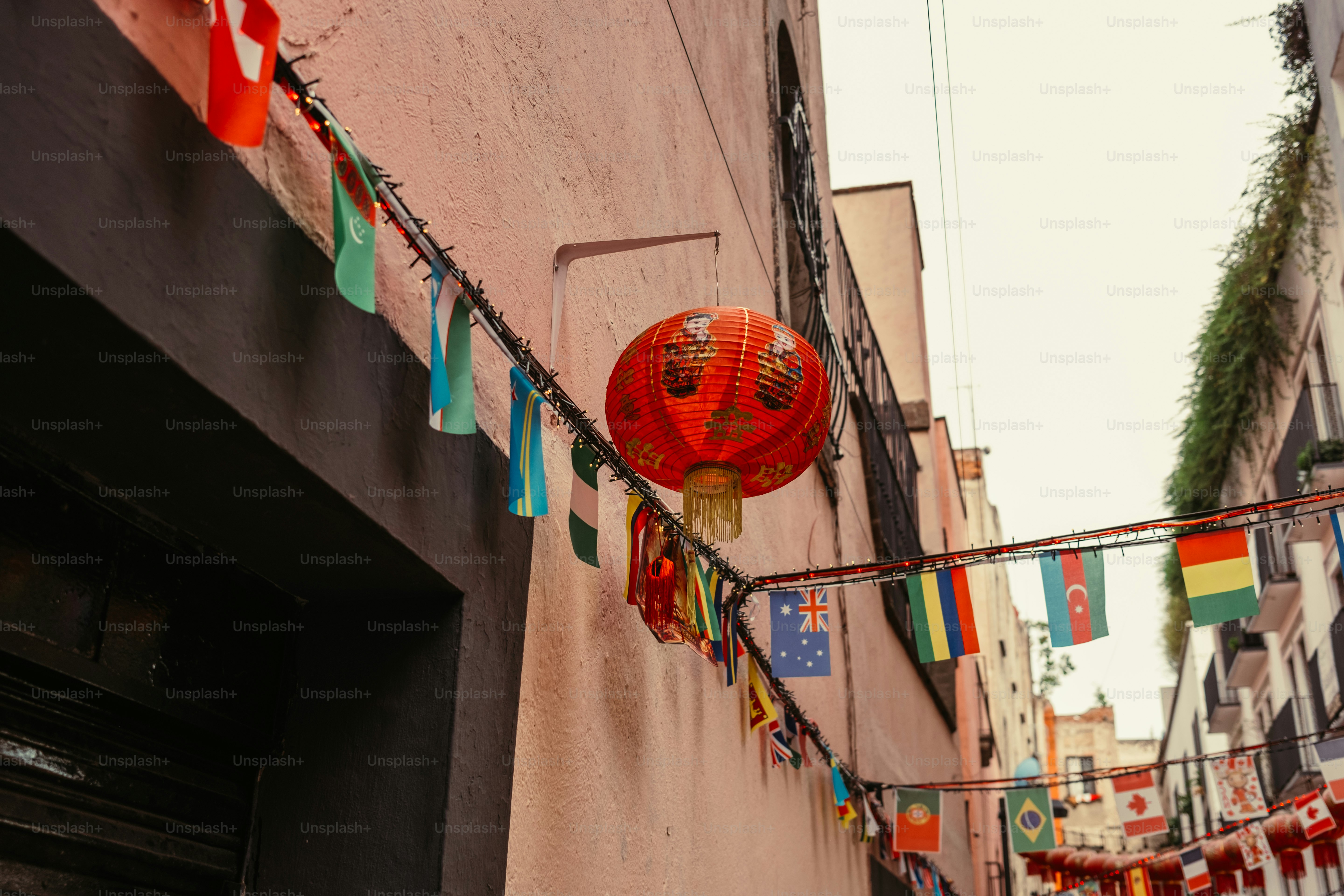 A red paper lantern hanging above a street decorated with international flags