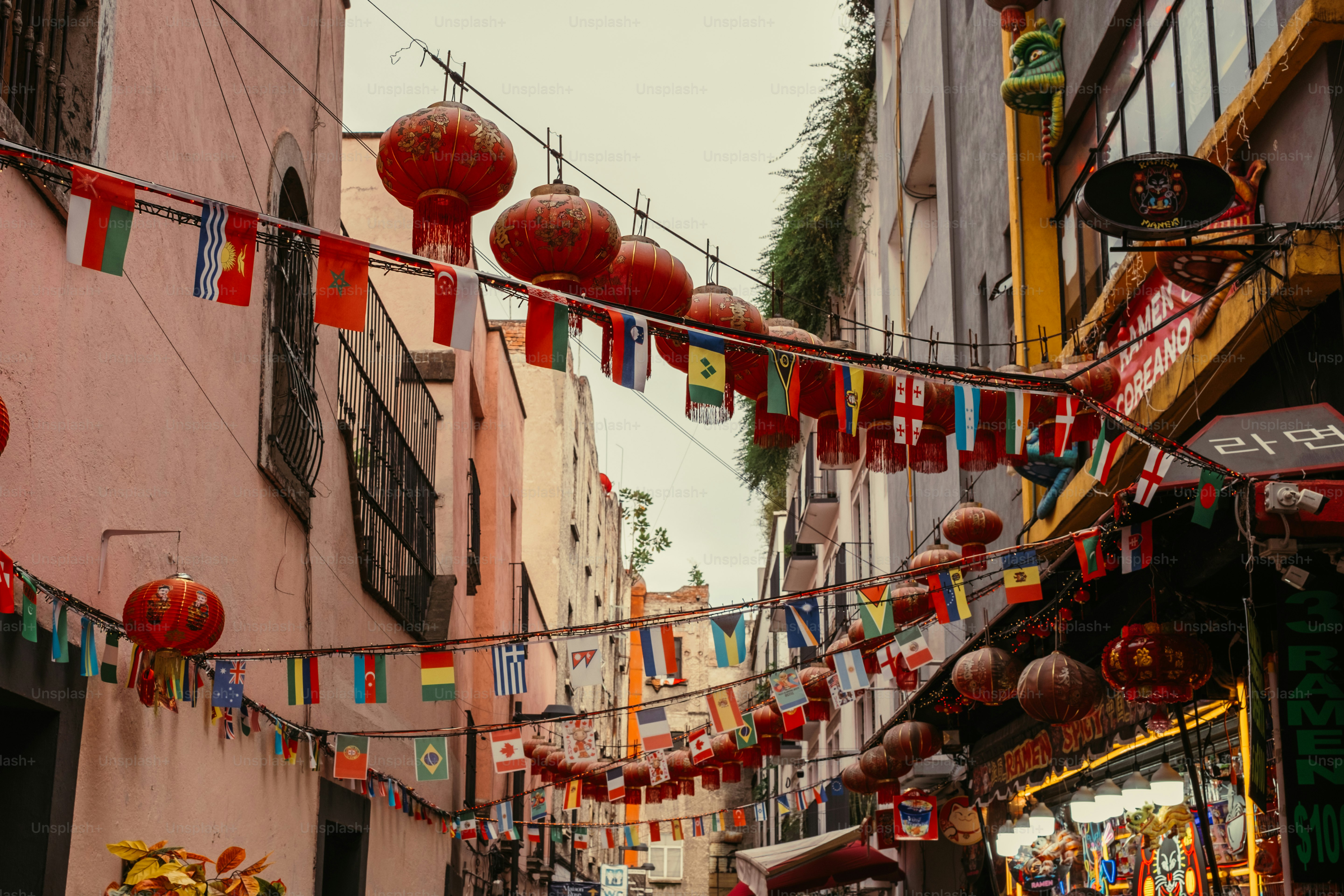 Red paper lanterns and international flags hanging above a narrow city street