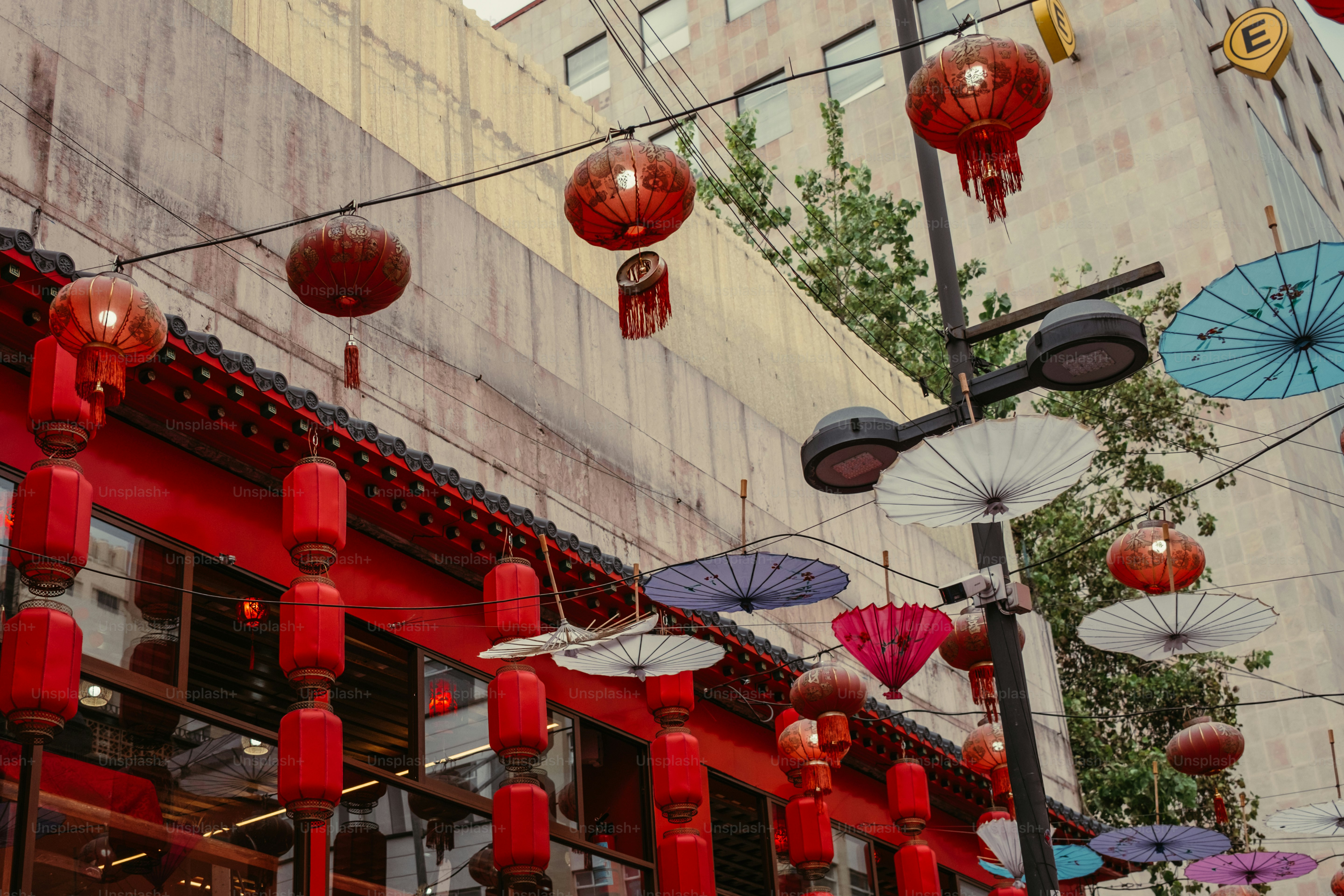 Red paper lanterns and colorful paper umbrellas hanging above a street