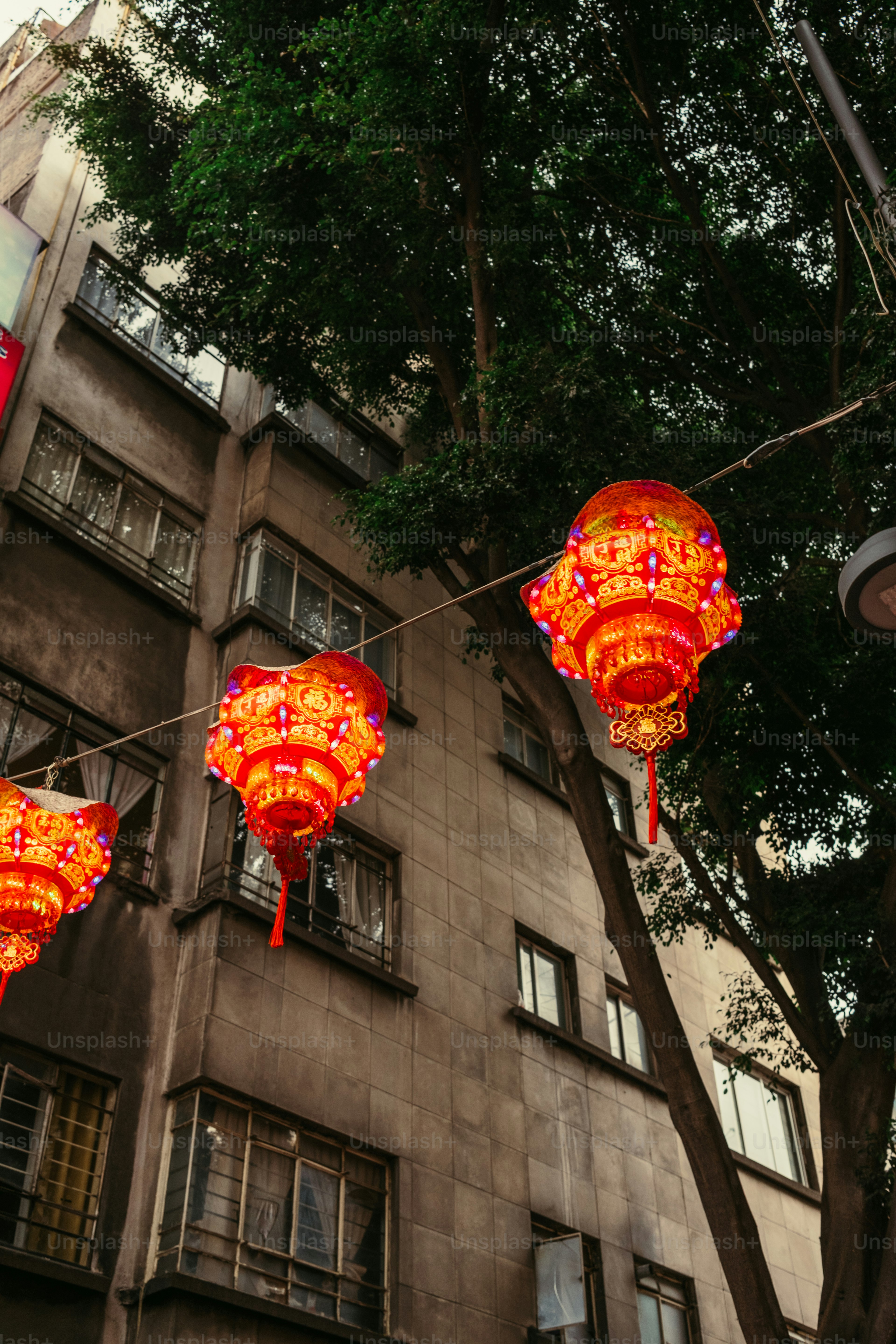 Bright red decorative lanterns hanging on a wire in front of a building