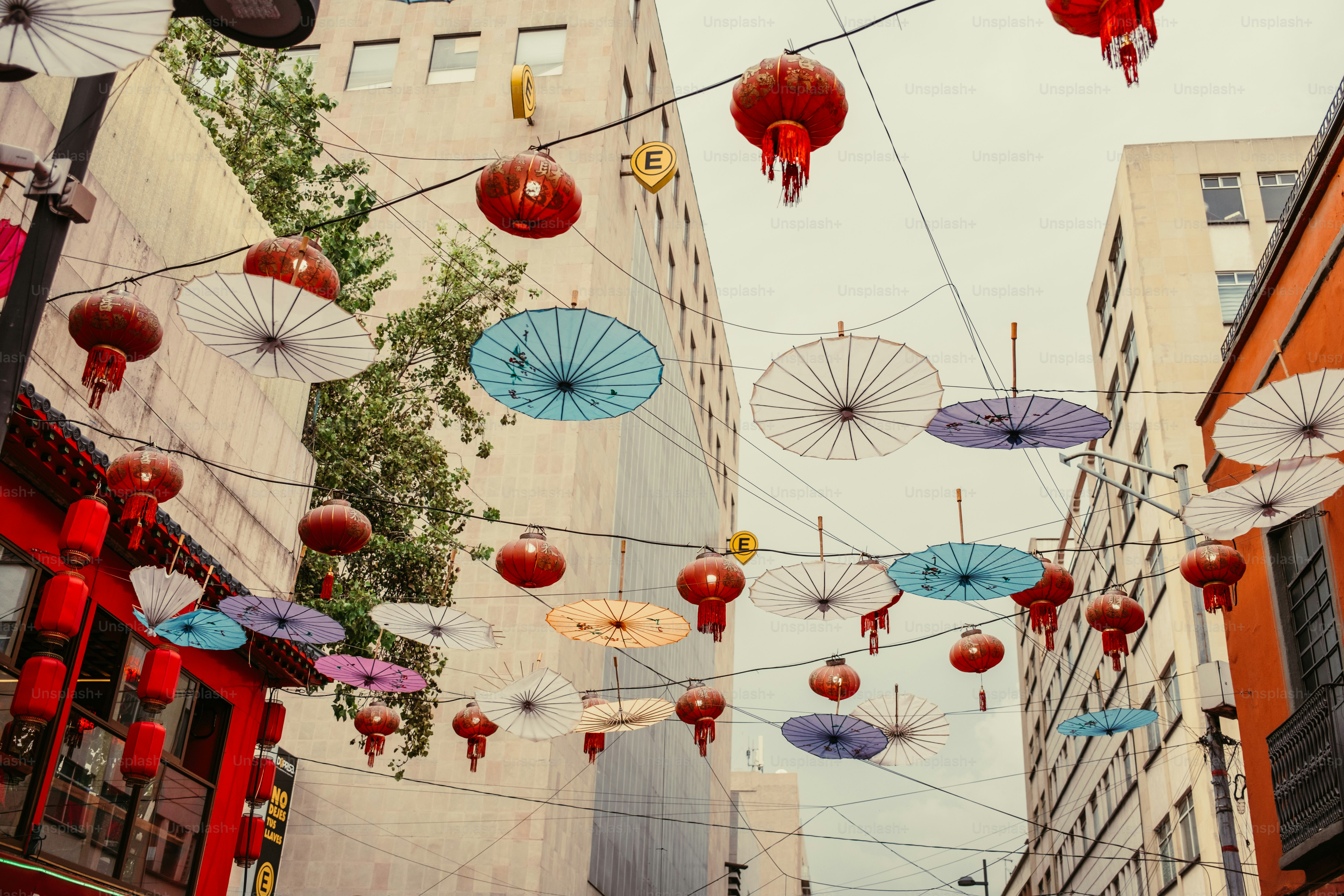 Des lanternes rouges et des parasols en papier colorés suspendus au-dessus d’une rue de la ville