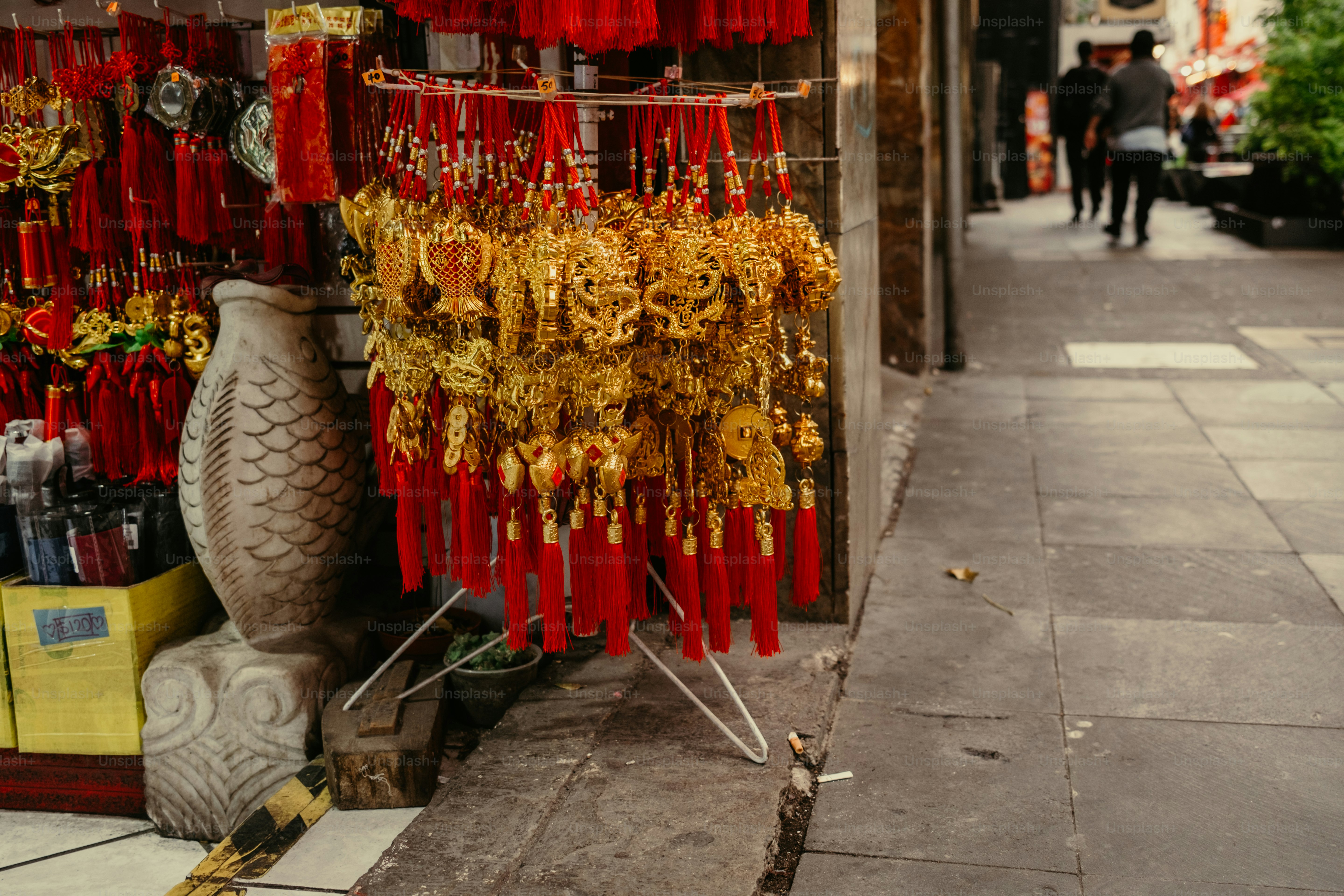 Des ornements dorés avec des pompons rouges accrochés à un porte-manteaux sur le trottoir d’une ville