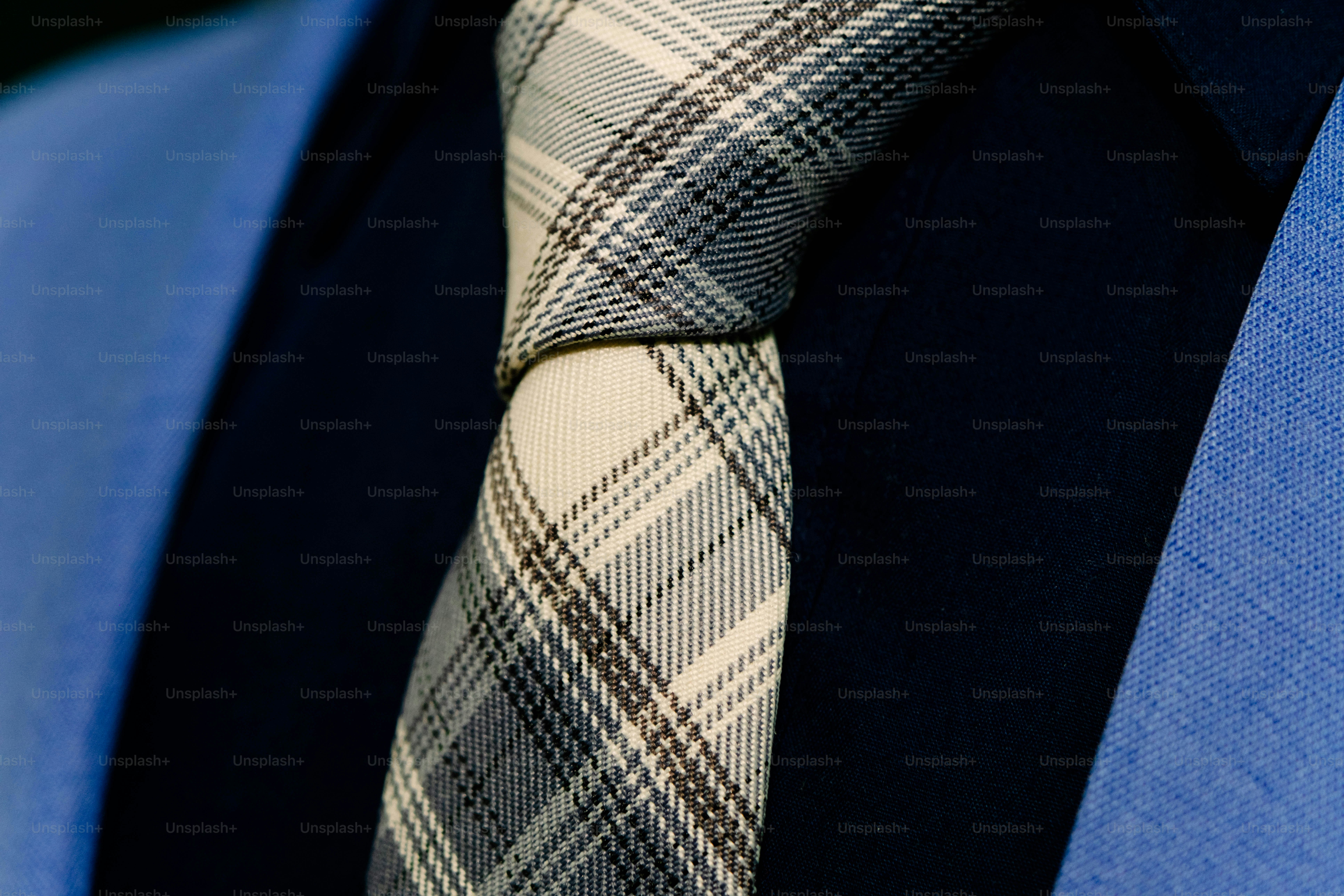 A plaid tie in shades of grey and white worn with a dark shirt