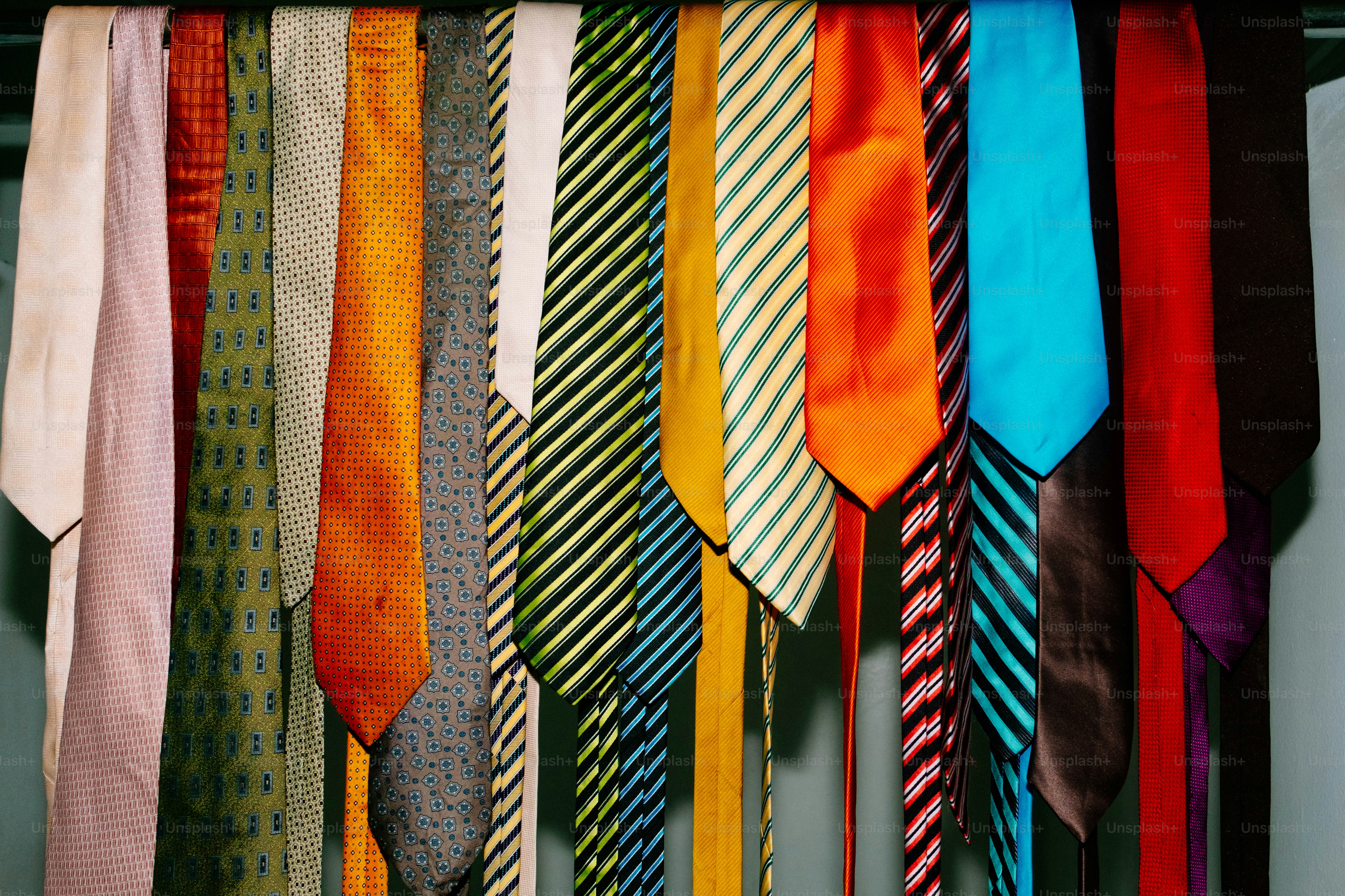 A row of colorful neckties in various patterns and textures hanging side by side