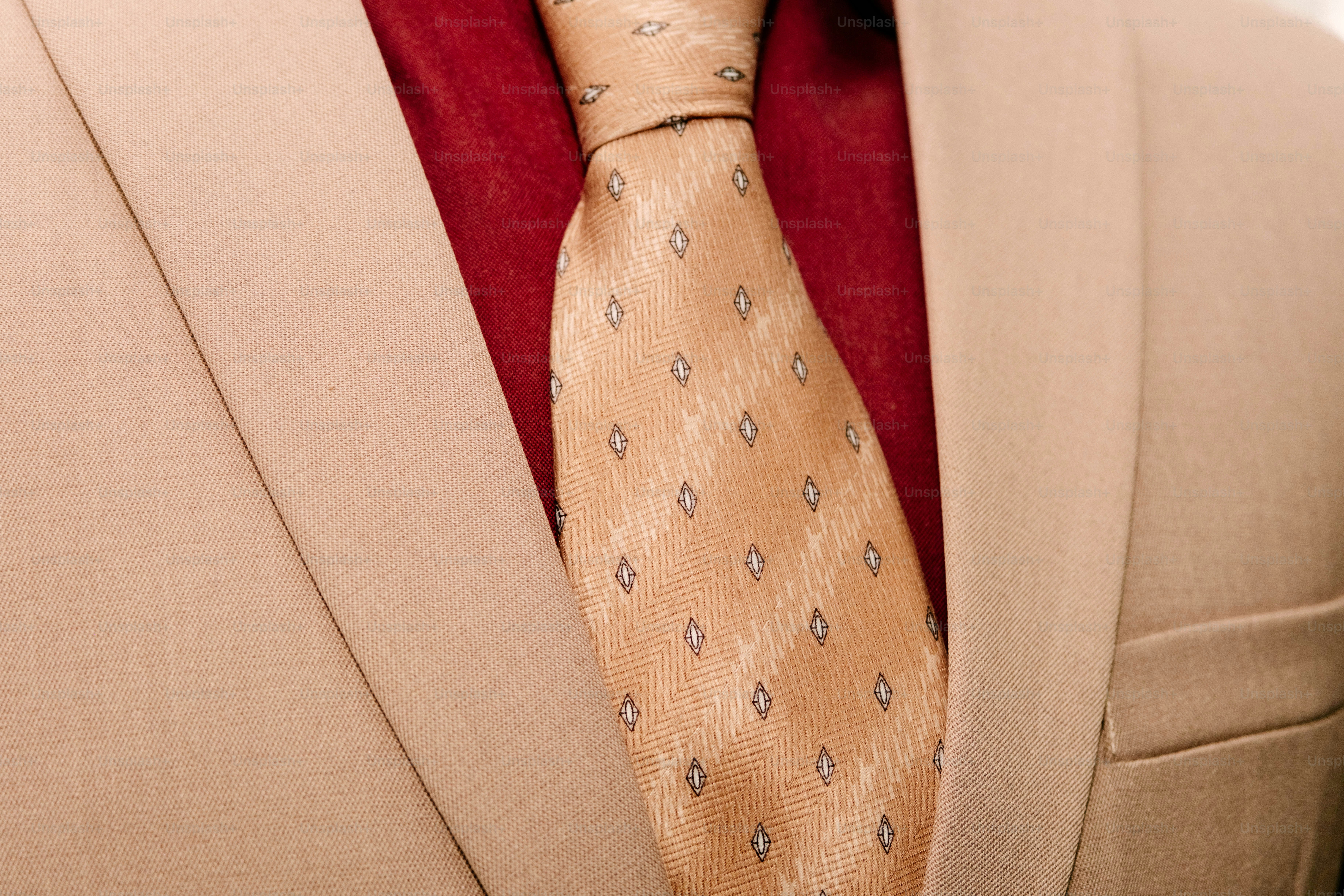 A tan suit jacket with a red shirt and a patterned tan tie