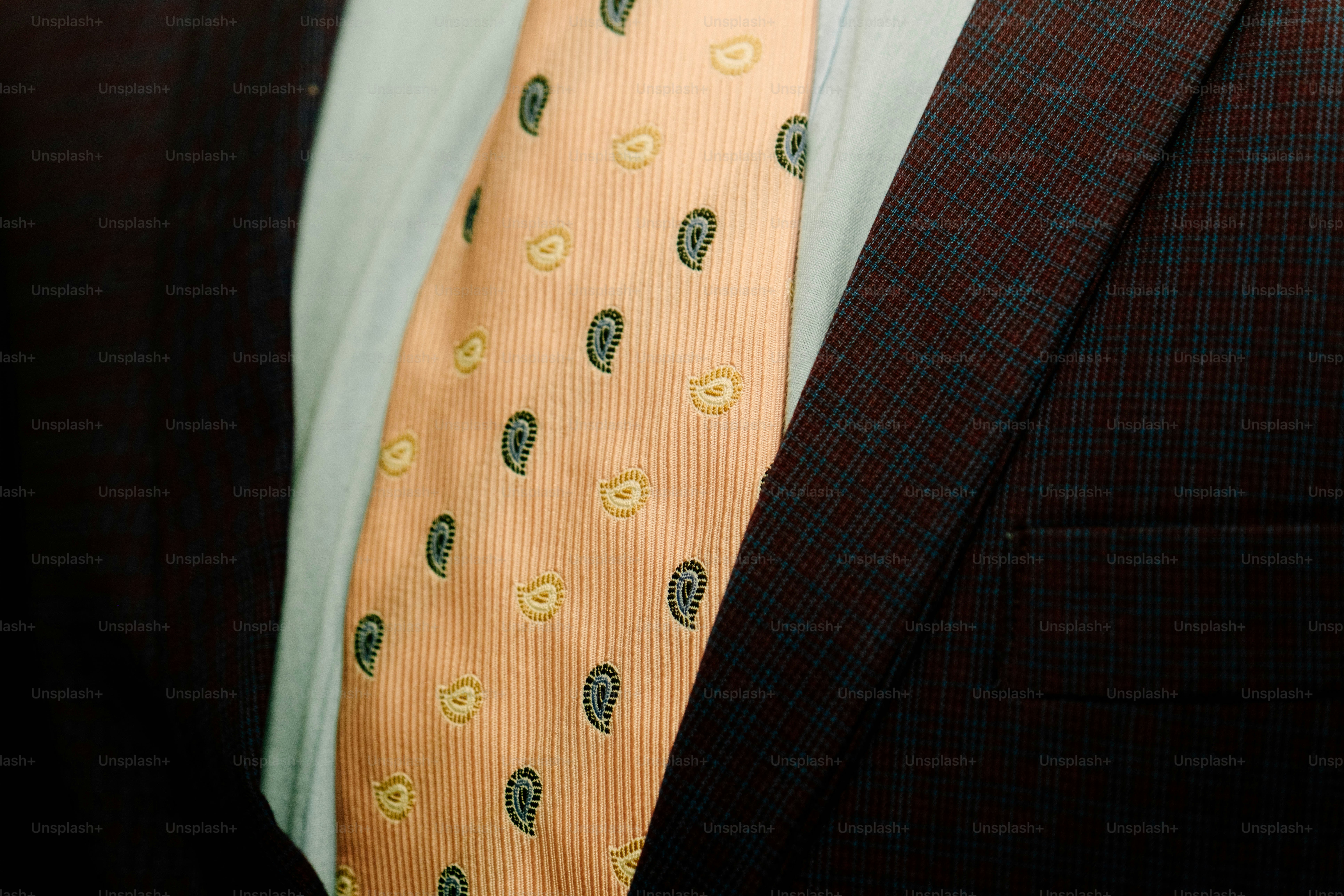A peach-colored paisley tie worn with a light shirt and a dark blazer
