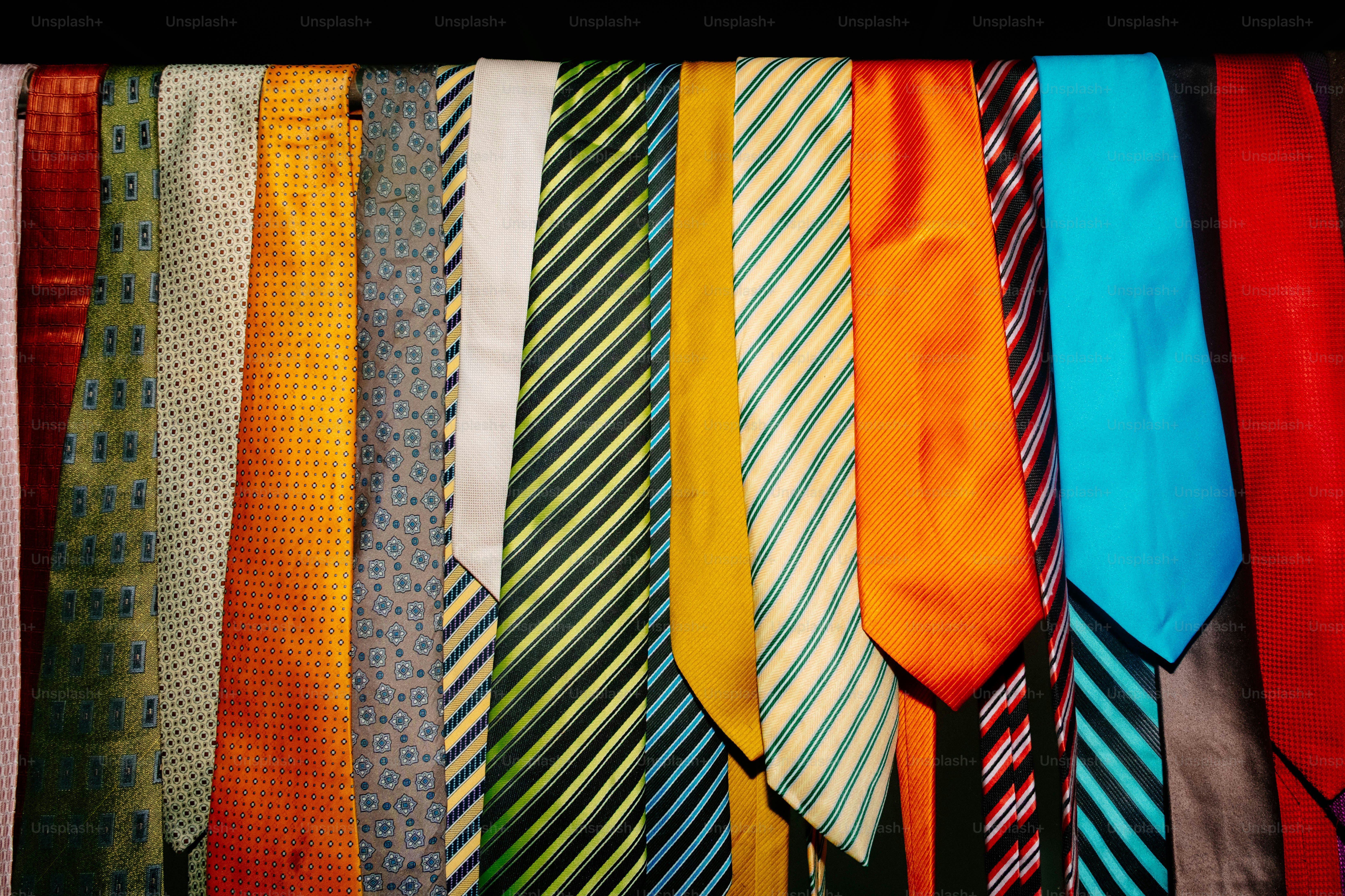 A row of colorful neckties with various patterns hanging side by side