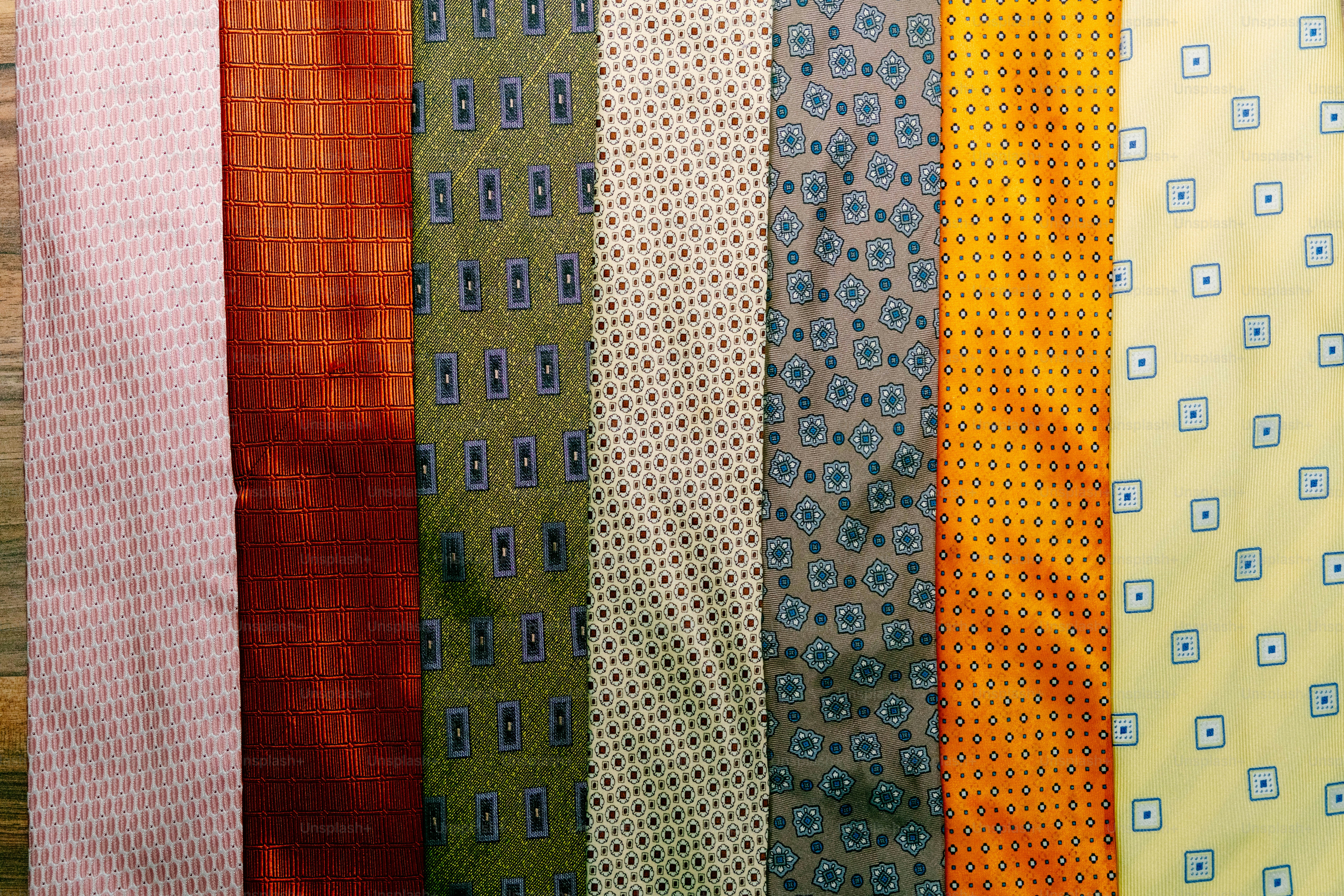 Seven colorful neckties with various geometric patterns arranged side by side