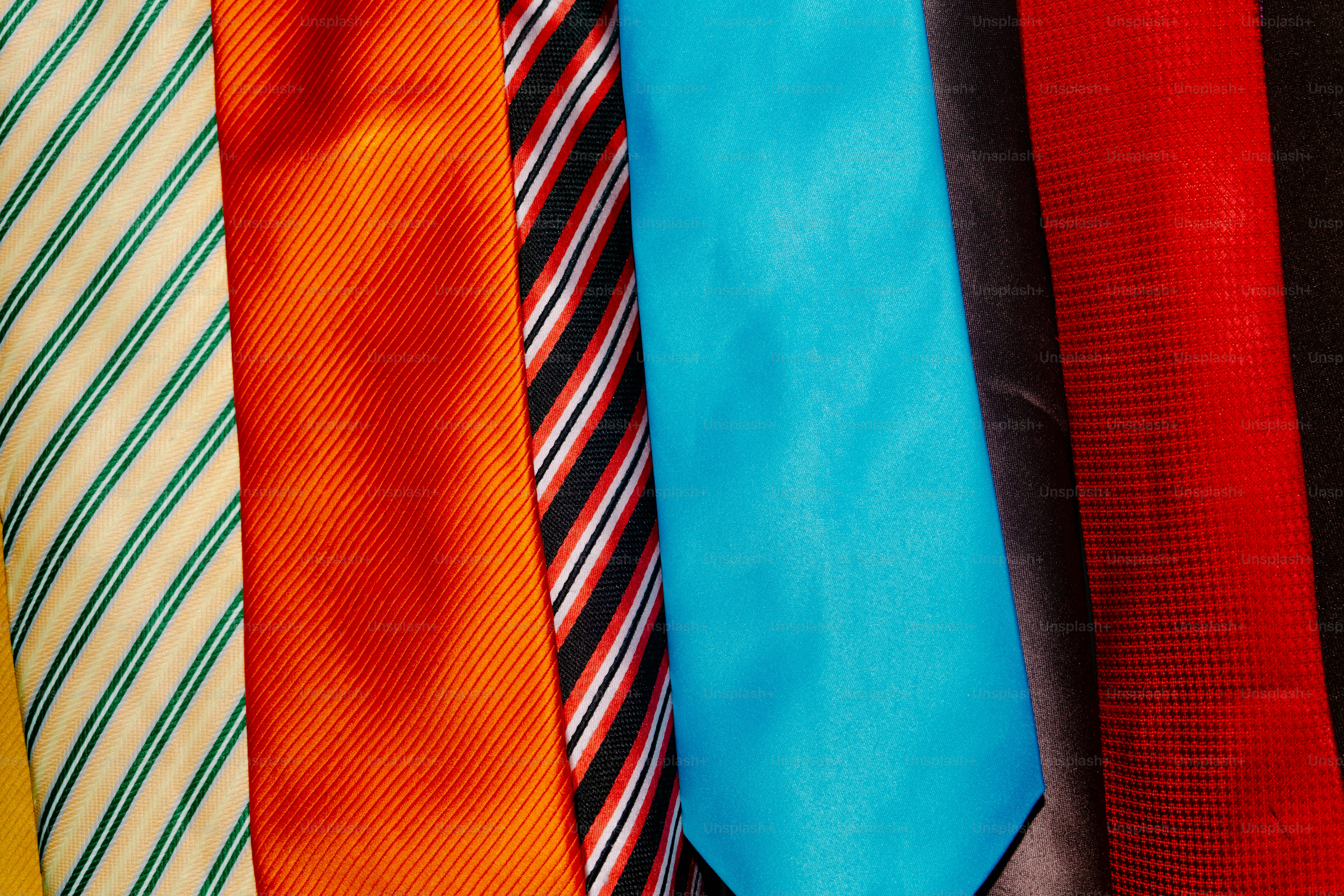 A collection of colorful neckties with various patterns and textures arranged side by side