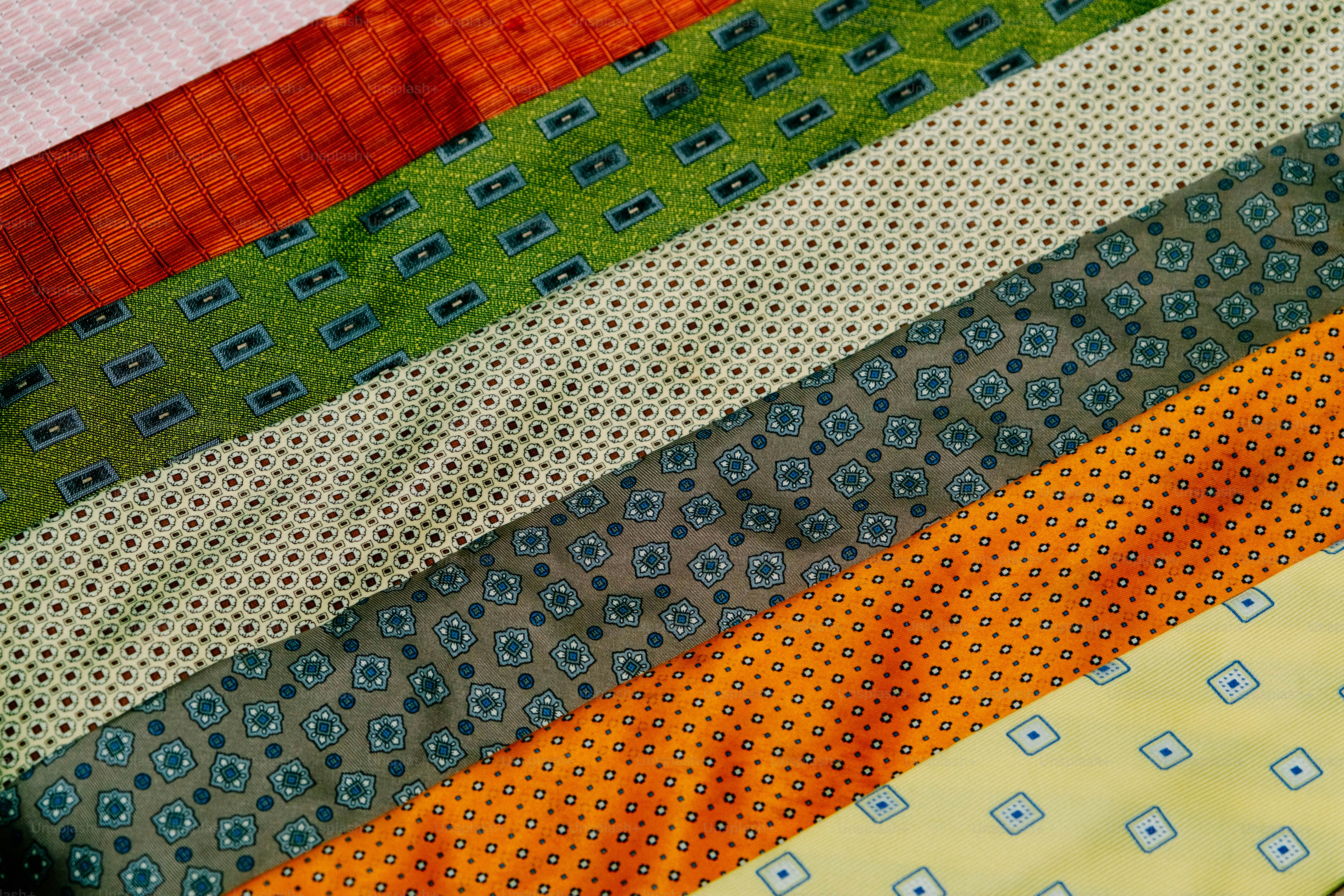 A collection of colorful patterned neckties arranged diagonally across the frame