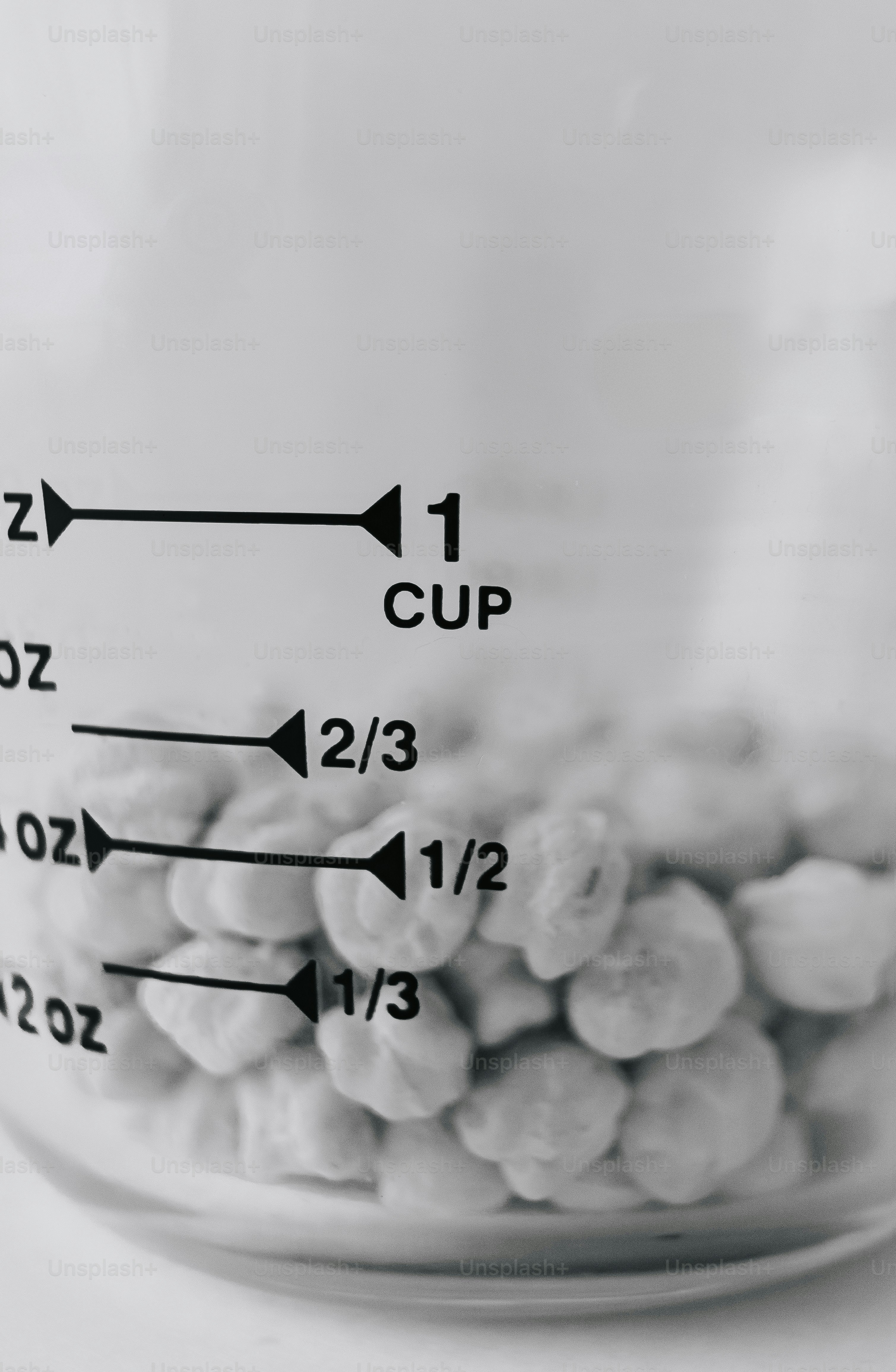 A glass measuring cup filled with chickpeas, showing volume markings in black ink.