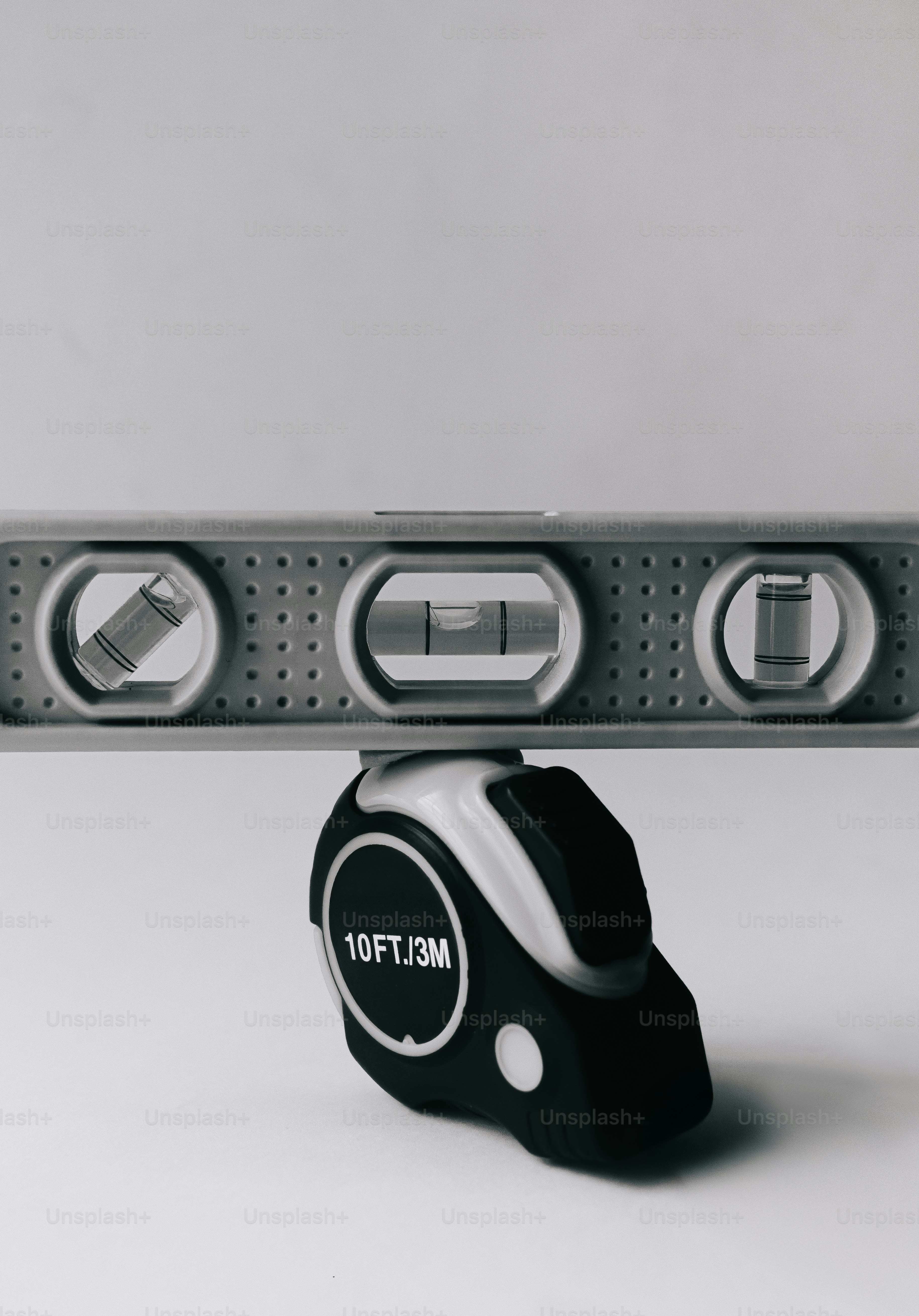 A spirit level balanced on top of a black and white tape measure.