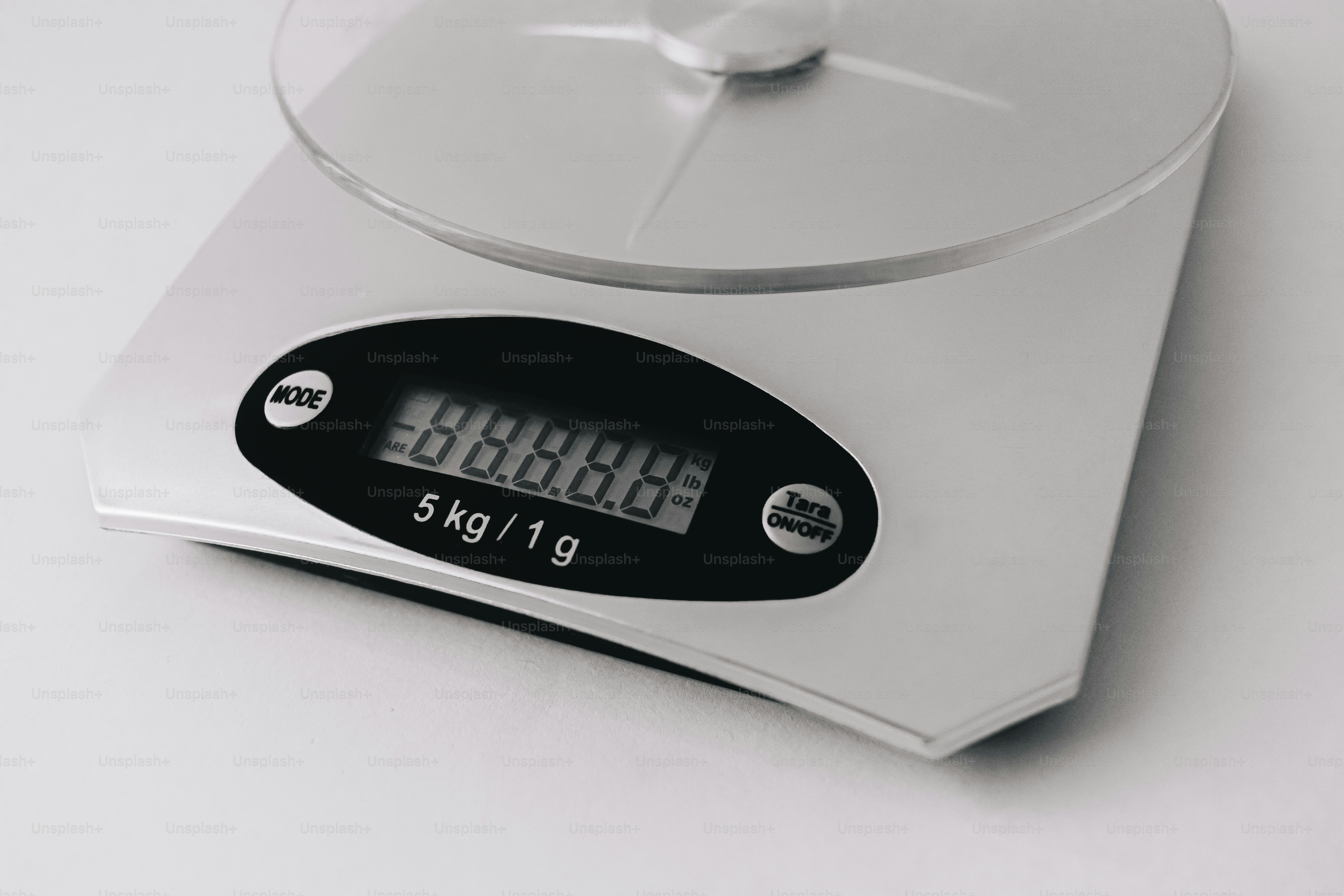 A silver digital kitchen scale with a circular platform on a white surface.