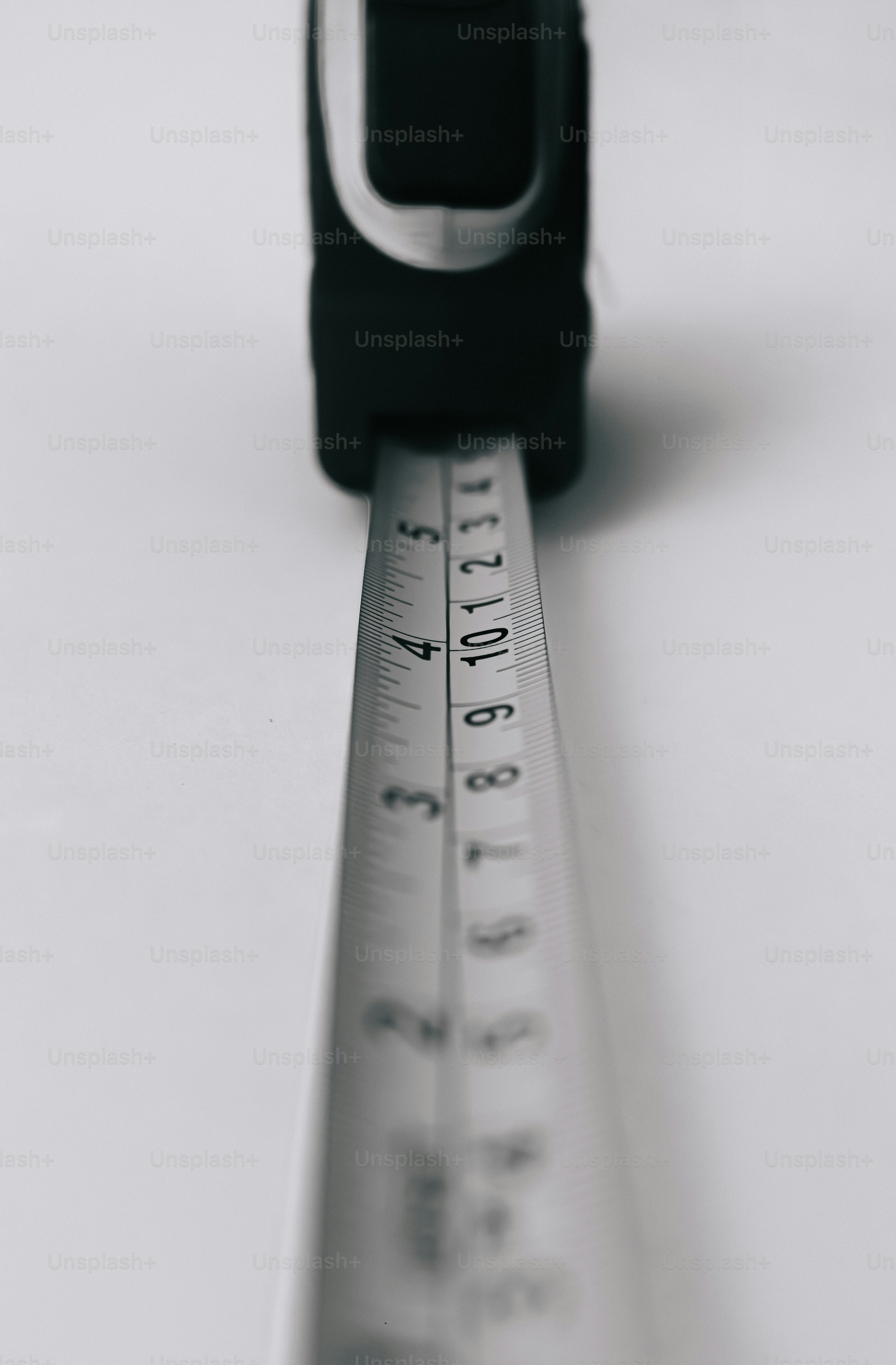 A black tape measure extended on a plain white surface.