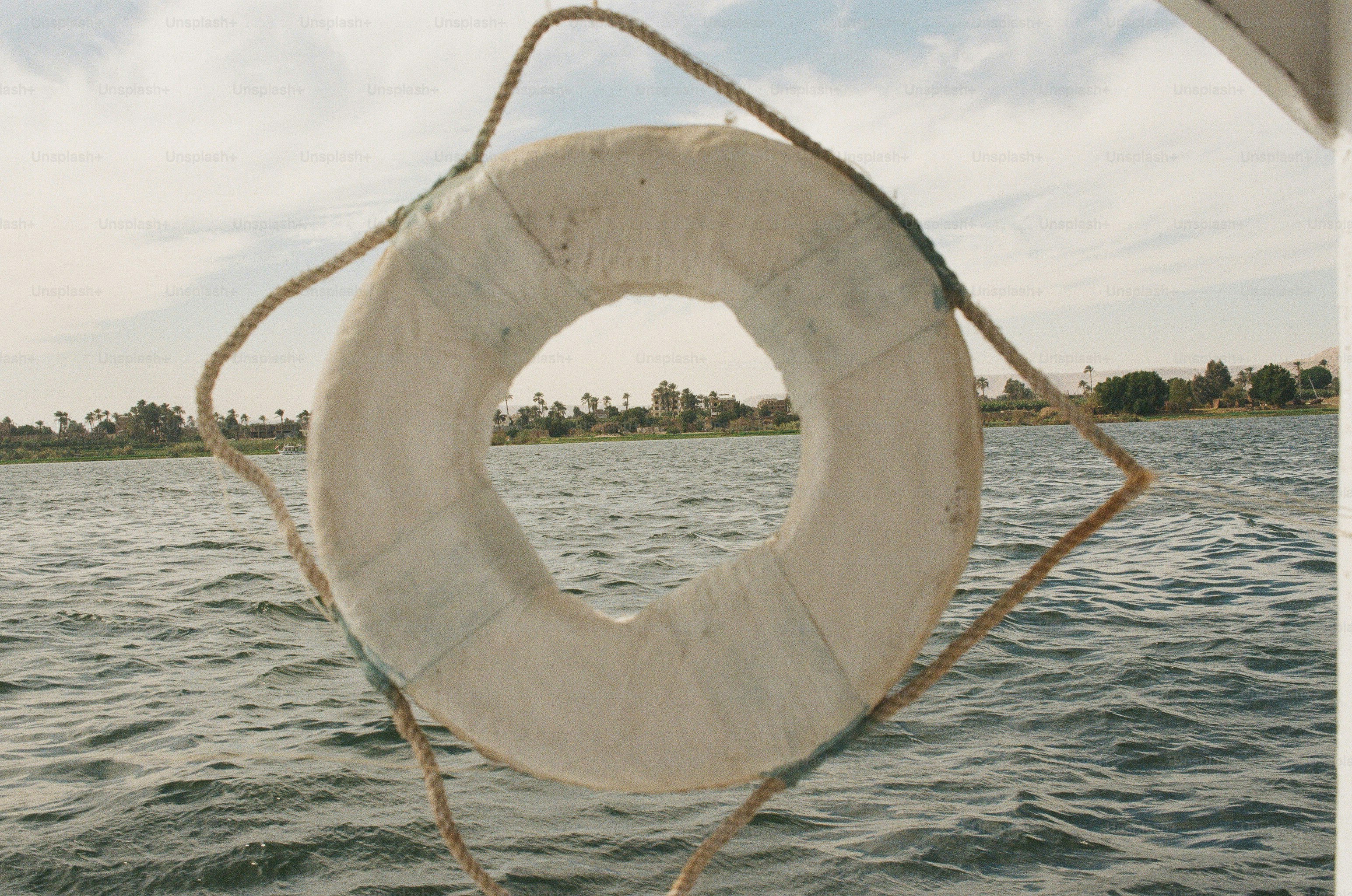 A white life ring framing the Nile River and the West Bank in Luxor