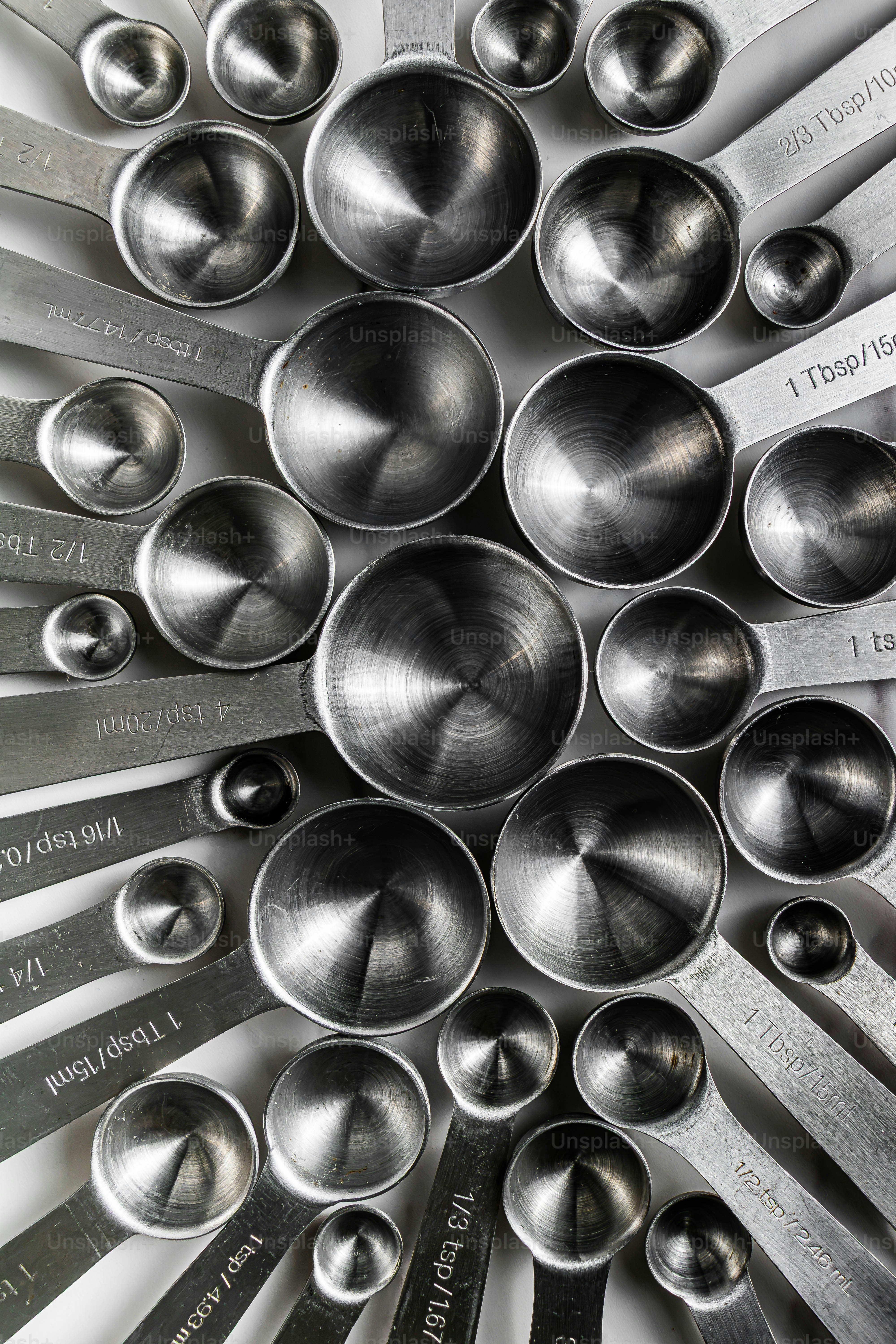 A collection of stainless steel measuring spoons arranged in a circular pattern