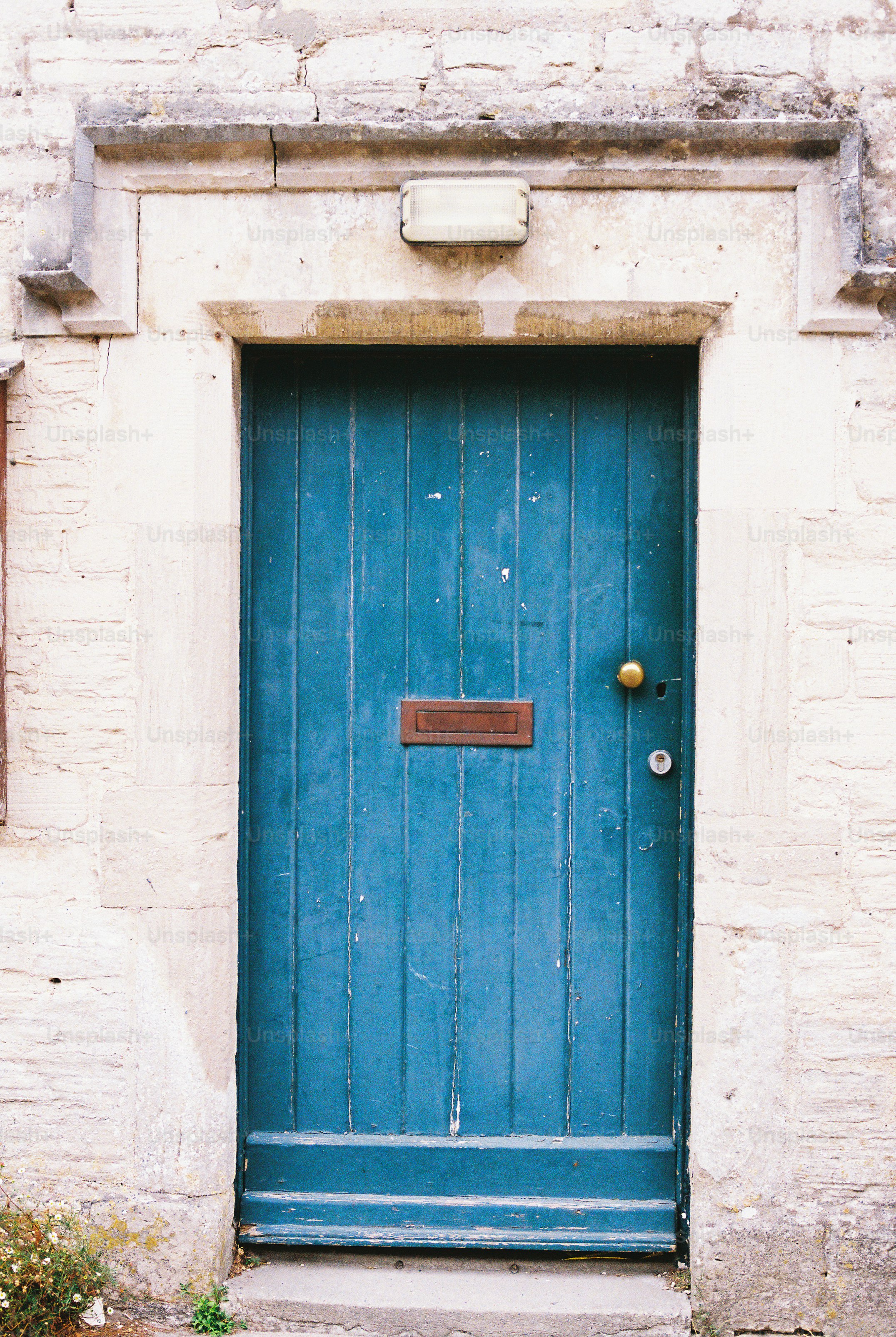 A weathered blue wooden door set in a light stone wall.