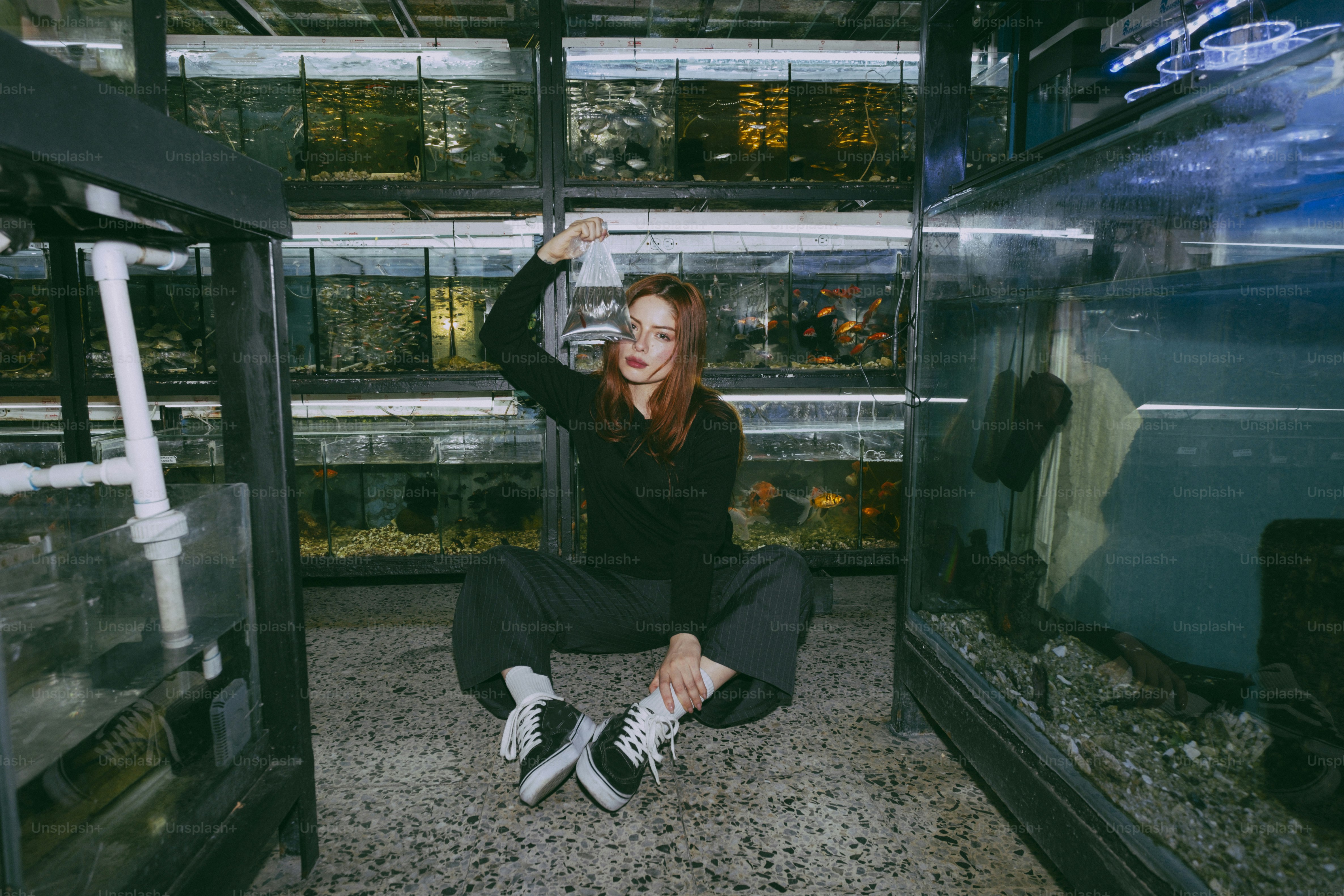 A woman in a black shirt holding a plastic bag of water in an aquarium