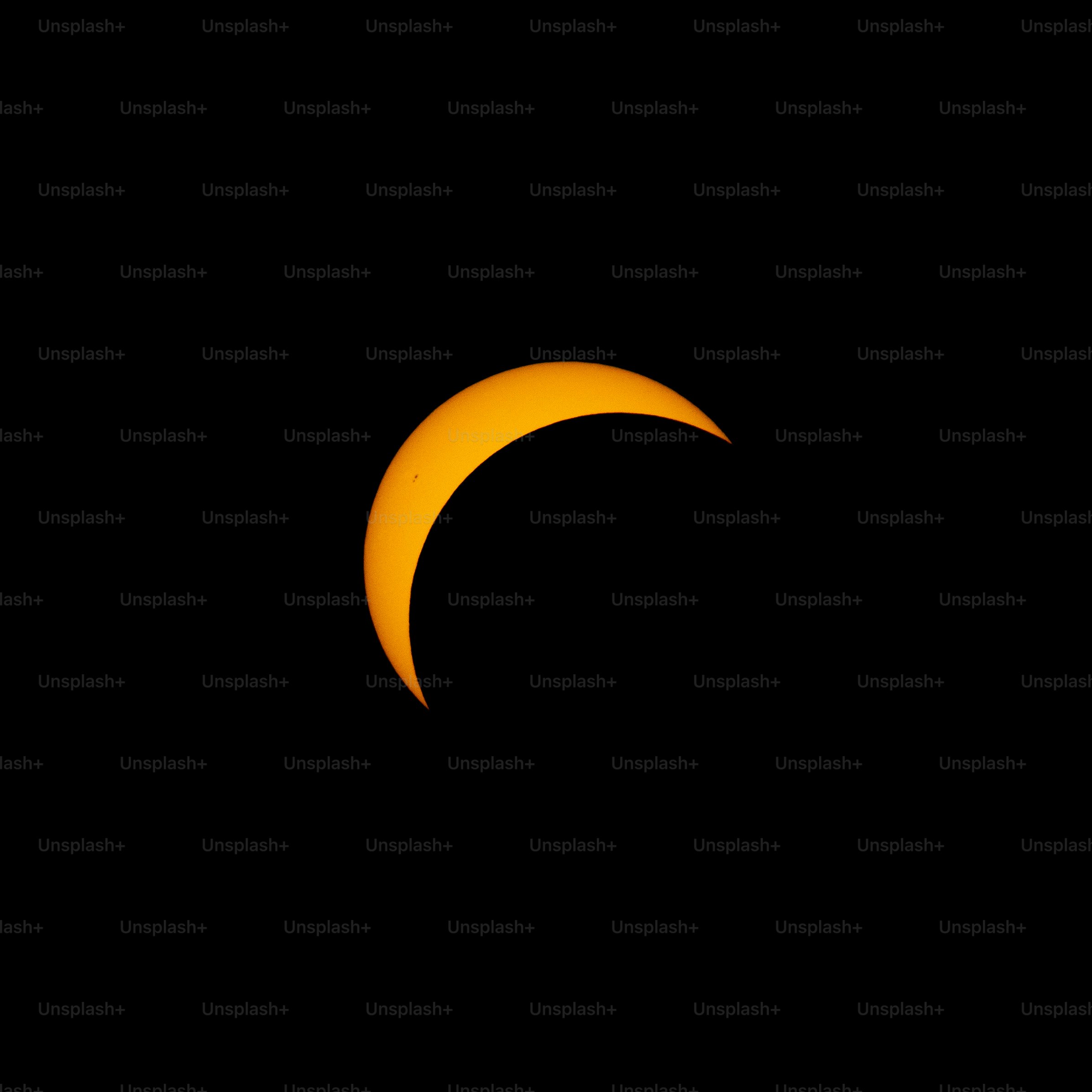 A crescent sun with a visible sunspot against a black sky