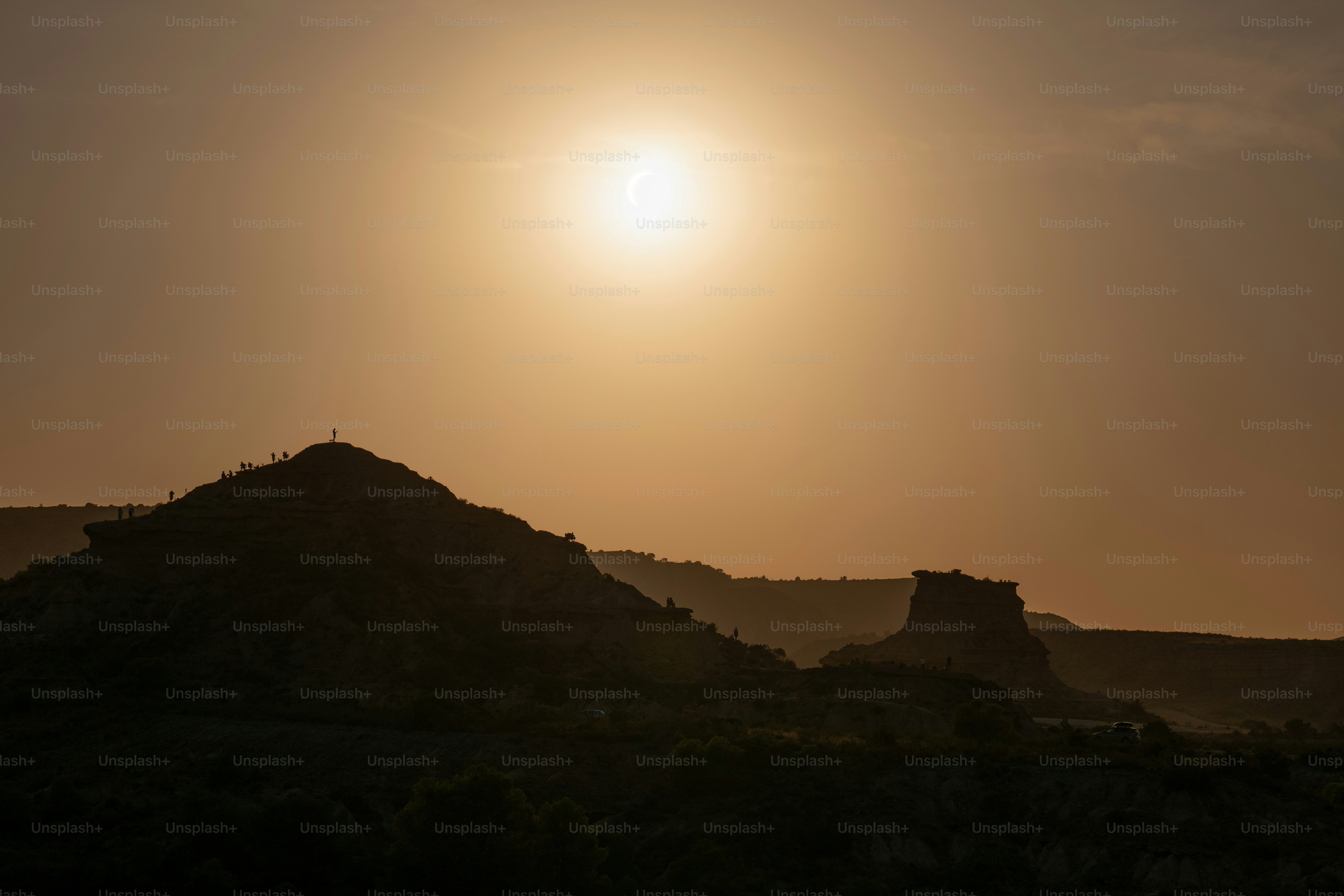 Silhouetted people on a rocky ridge against a bright golden sky