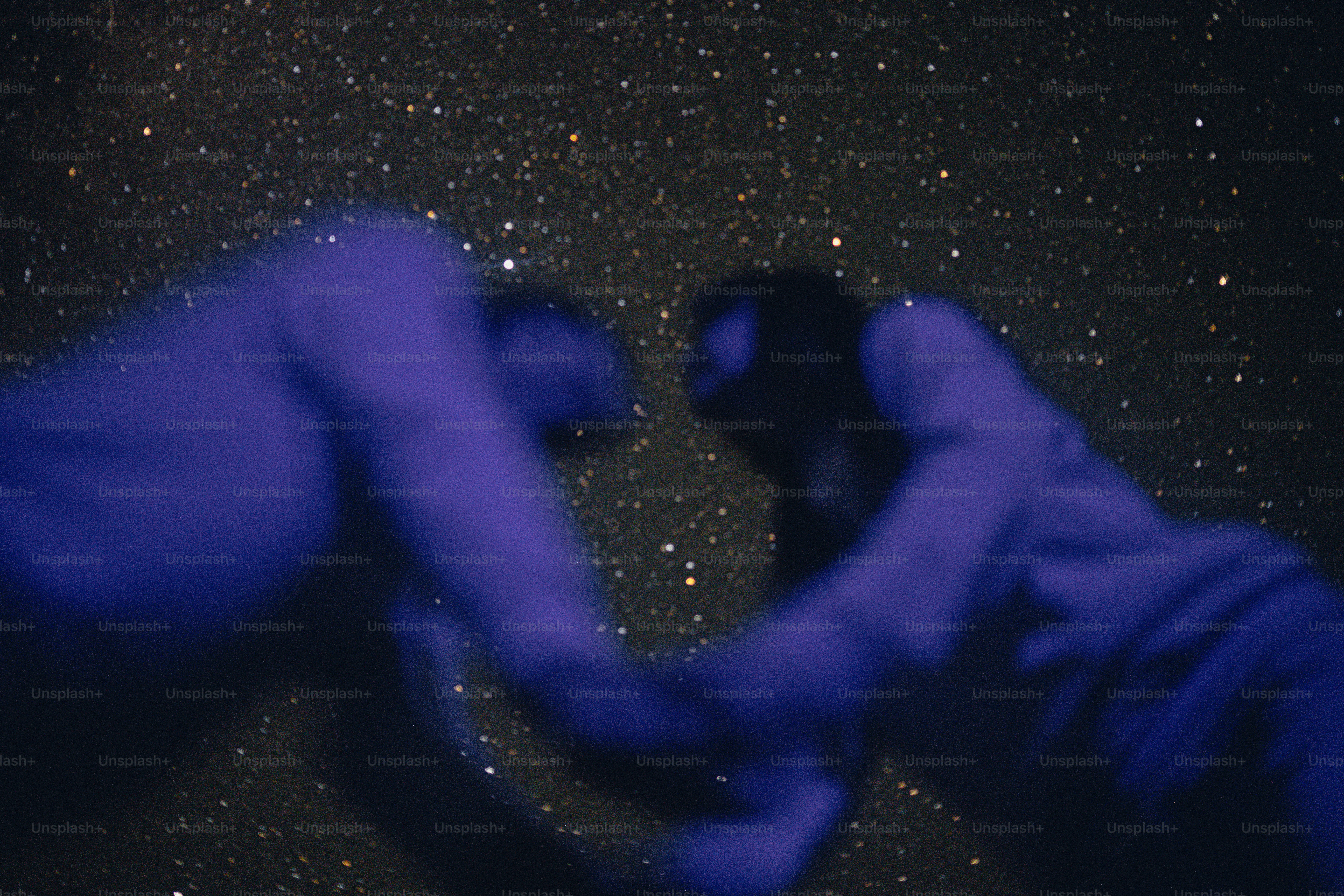 Two people in silhouette forming a heart shape with their hands against a starry sky