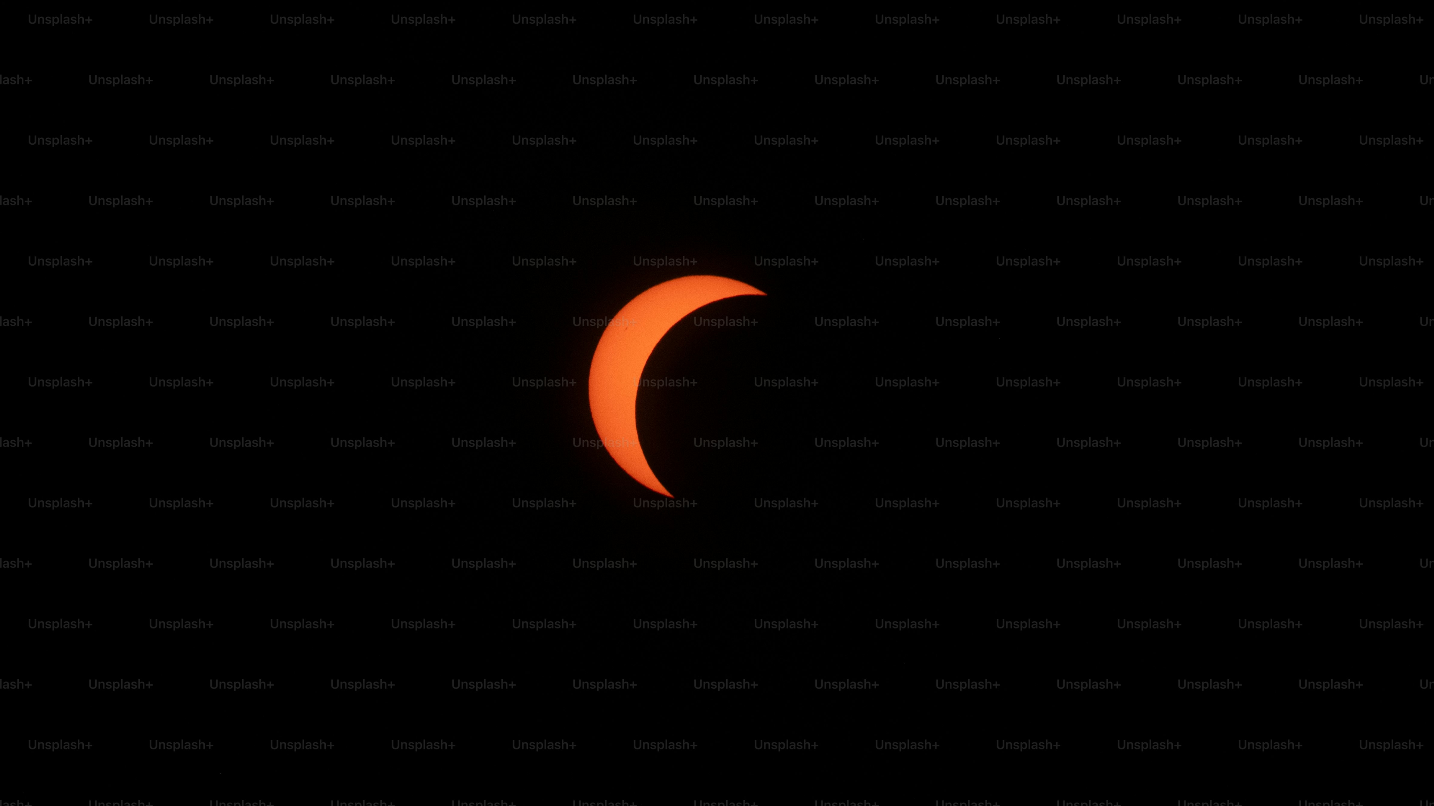 A crescent-shaped solar eclipse glowing against a dark black sky