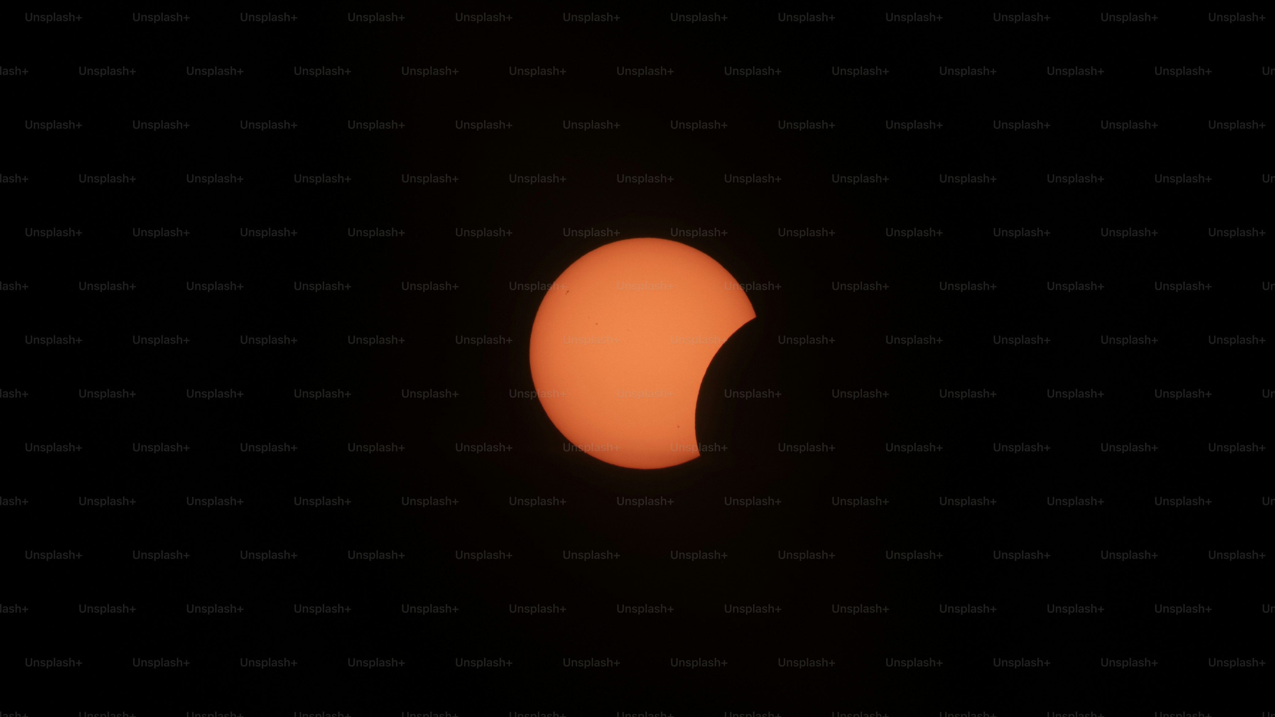 A partial solar eclipse showing a glowing orange crescent against a dark sky
