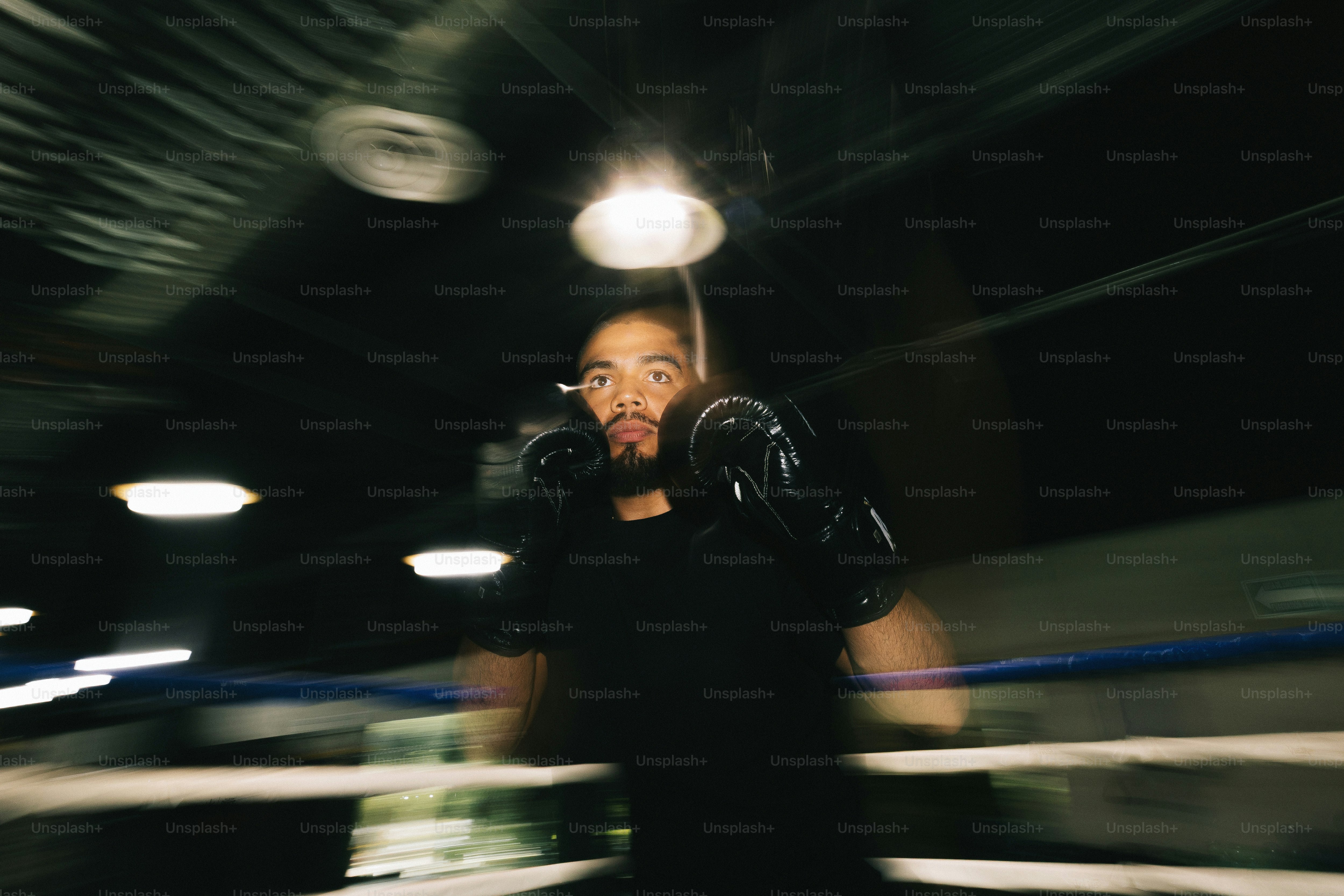 Petinju dengan sarung tangan hitam berlatih di ring dengan motion blur
