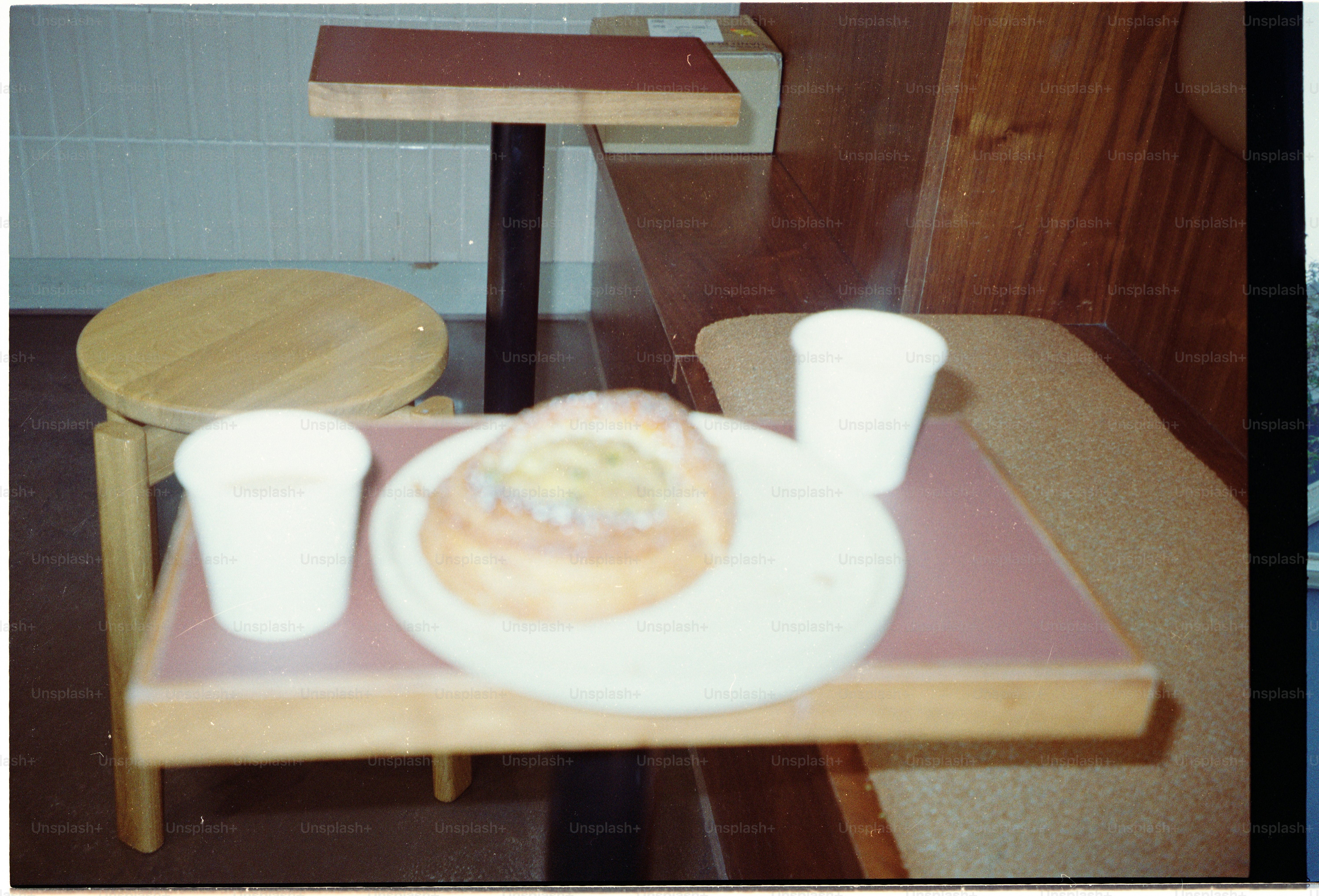 A pastry on a plate with two white cups on a wooden table.