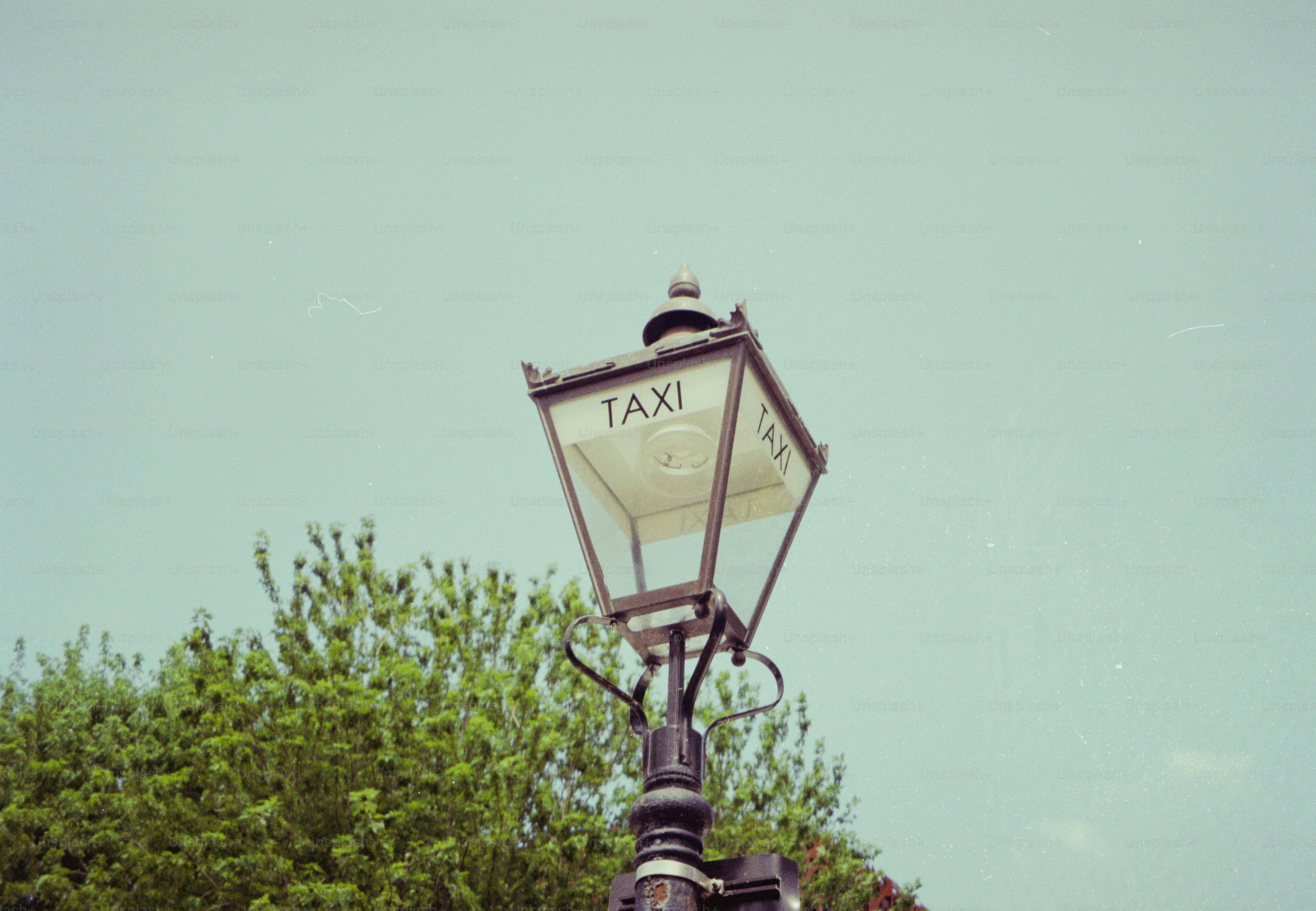 A vintage street lamp with a sign reading "TAXI" against a clear sky.