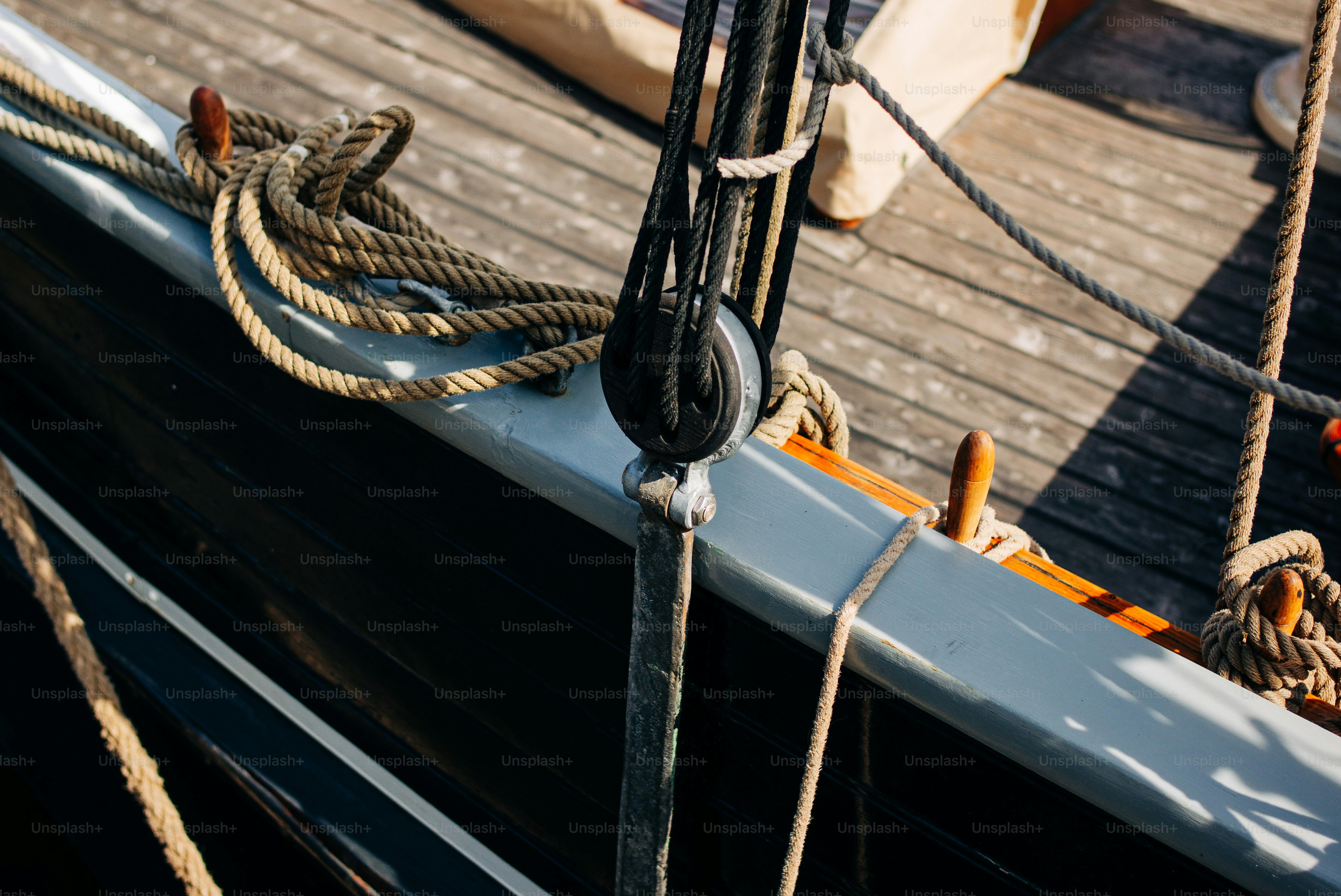 A wooden boat deck with coiled ropes and a black pulley block