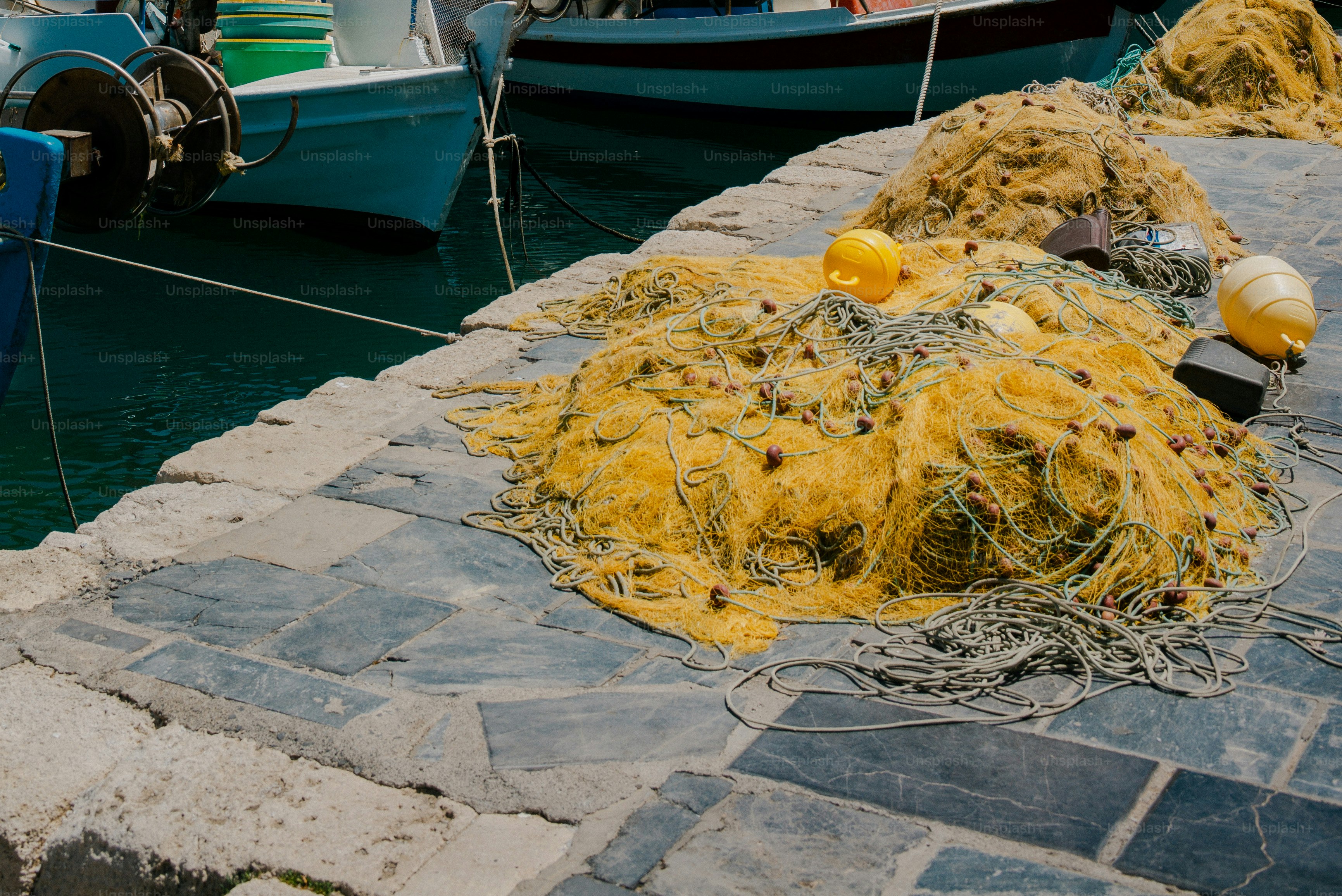 Yellow fishing nets piled on a stone pier beside a blue boat