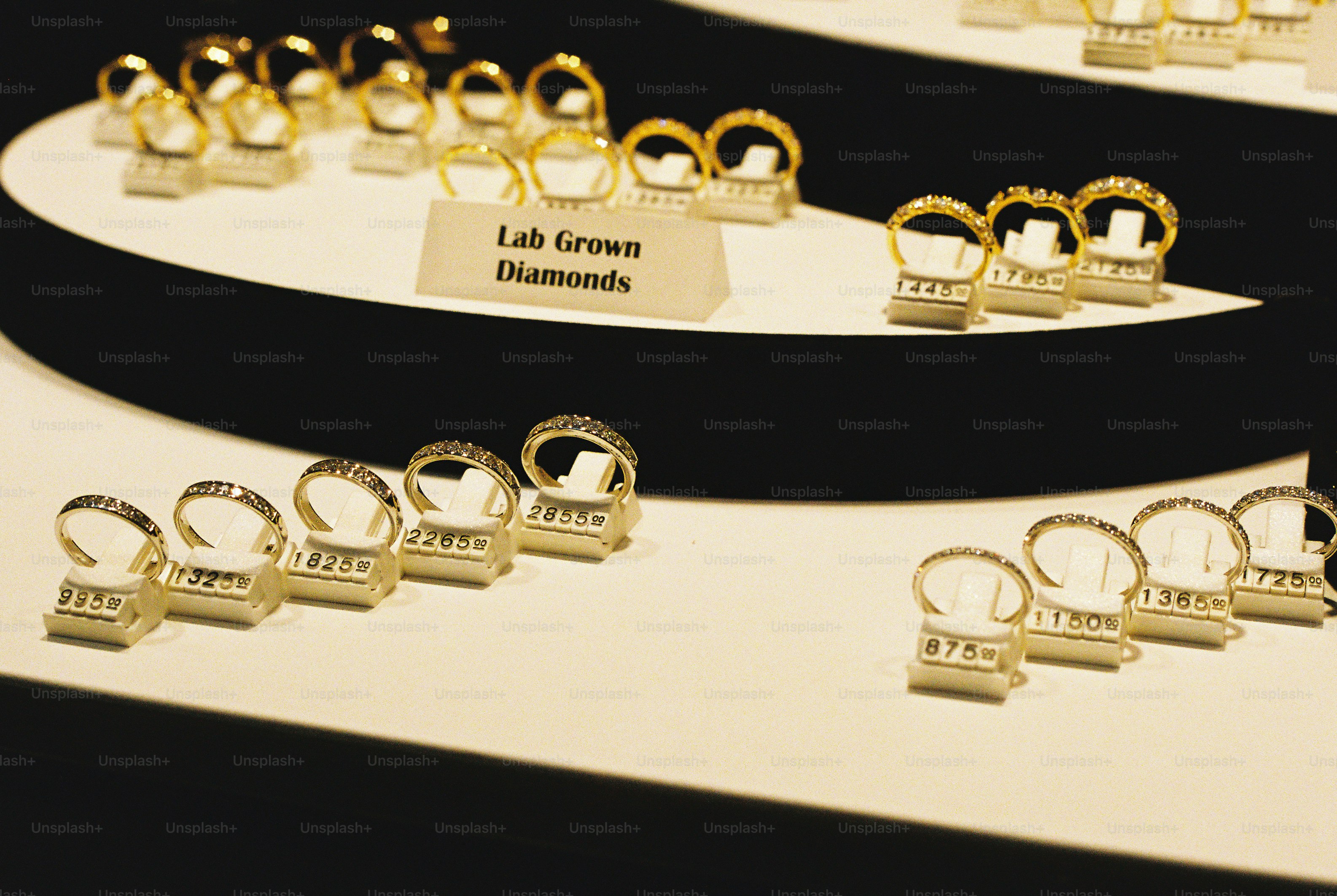 Gold rings with diamonds on white display stands with price tags in a store