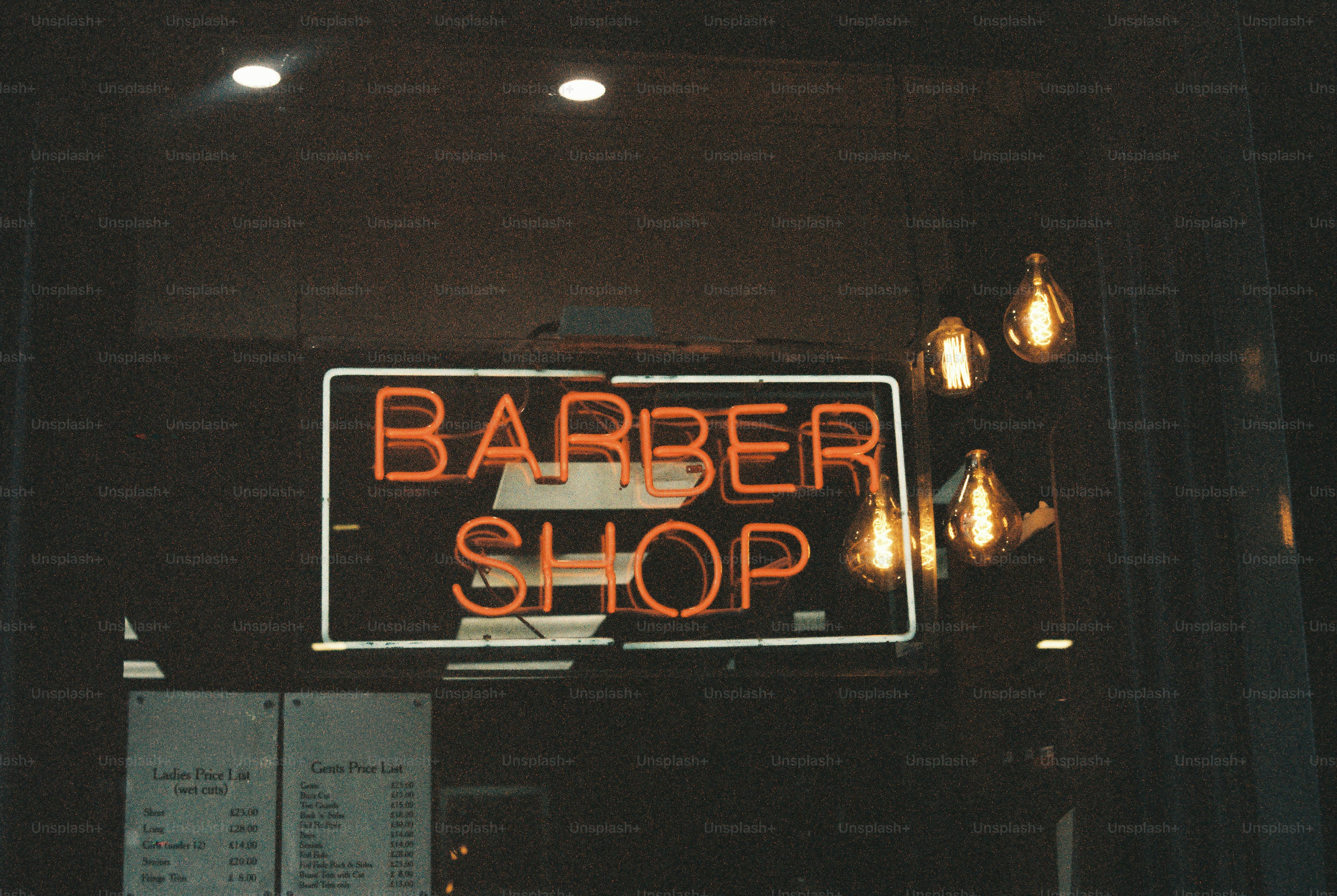 A glowing orange neon sign reading BARBER SHOP in a dark window