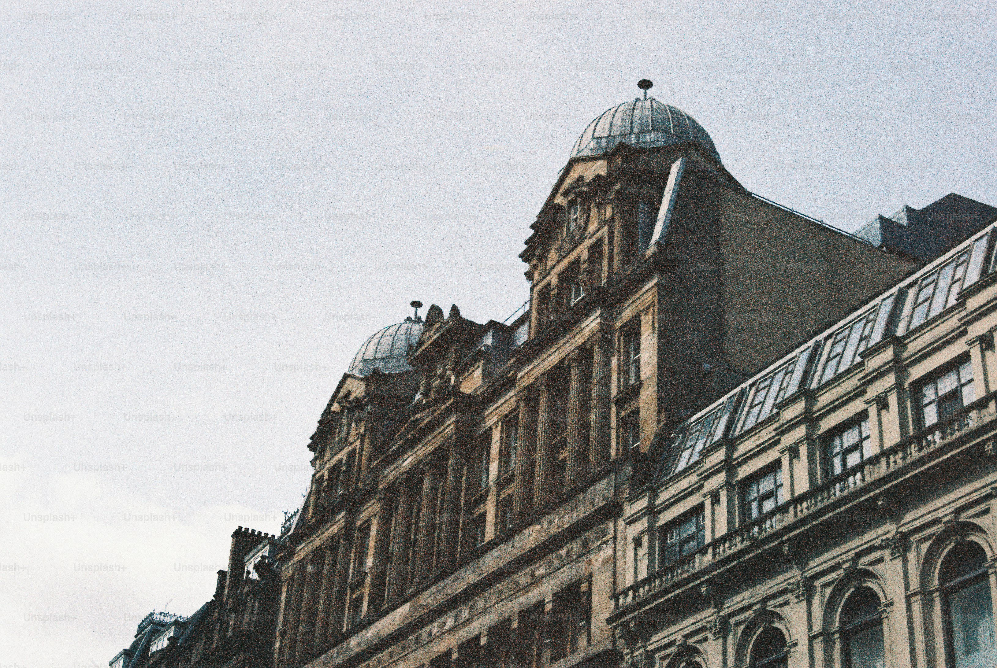 Ornate stone building with domed roofs against a pale overcast sky