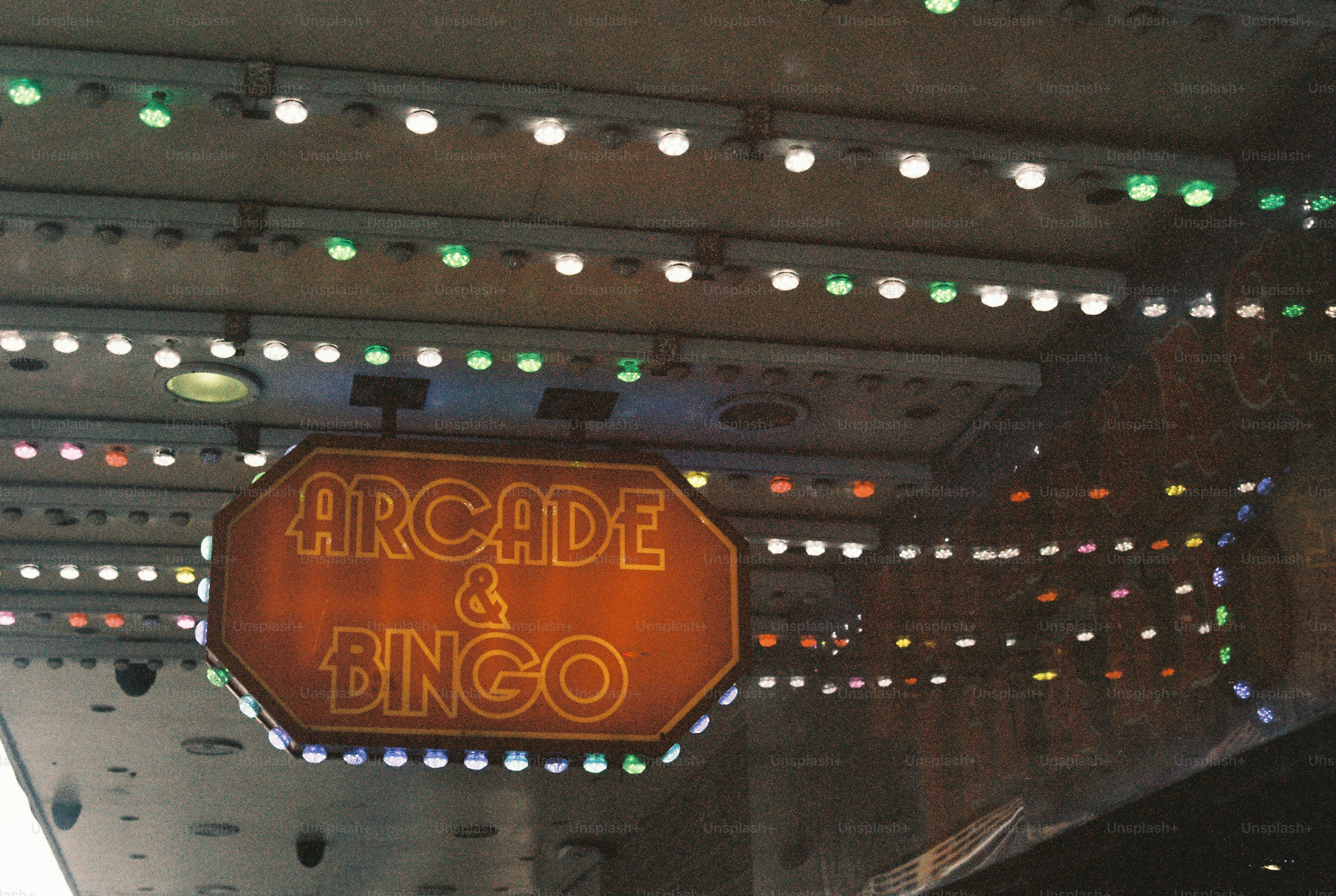 An illuminated sign reading Arcade & Bingo hanging beneath a ceiling with colorful lights