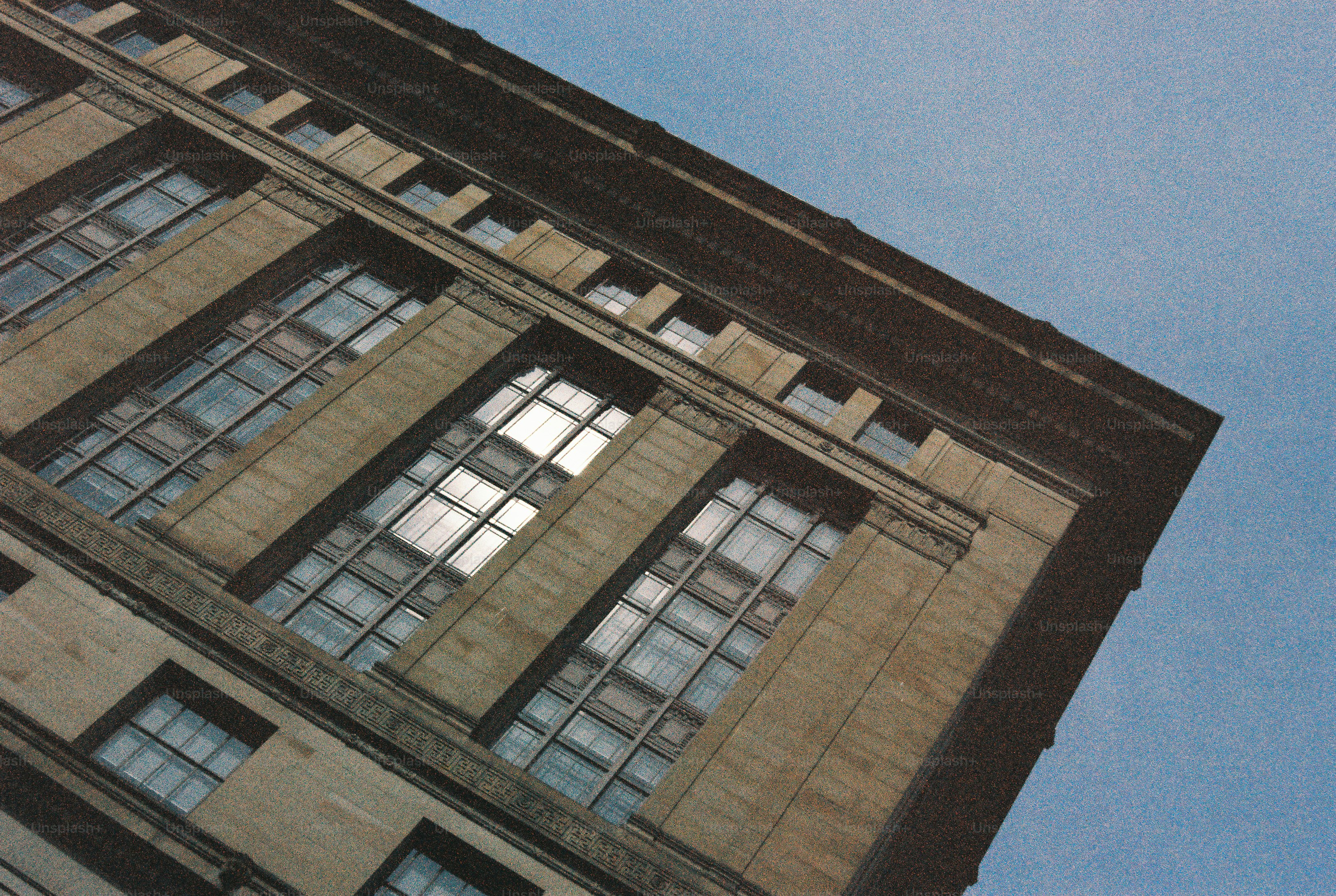 A low angle view of a stone building facade with tall grid windows