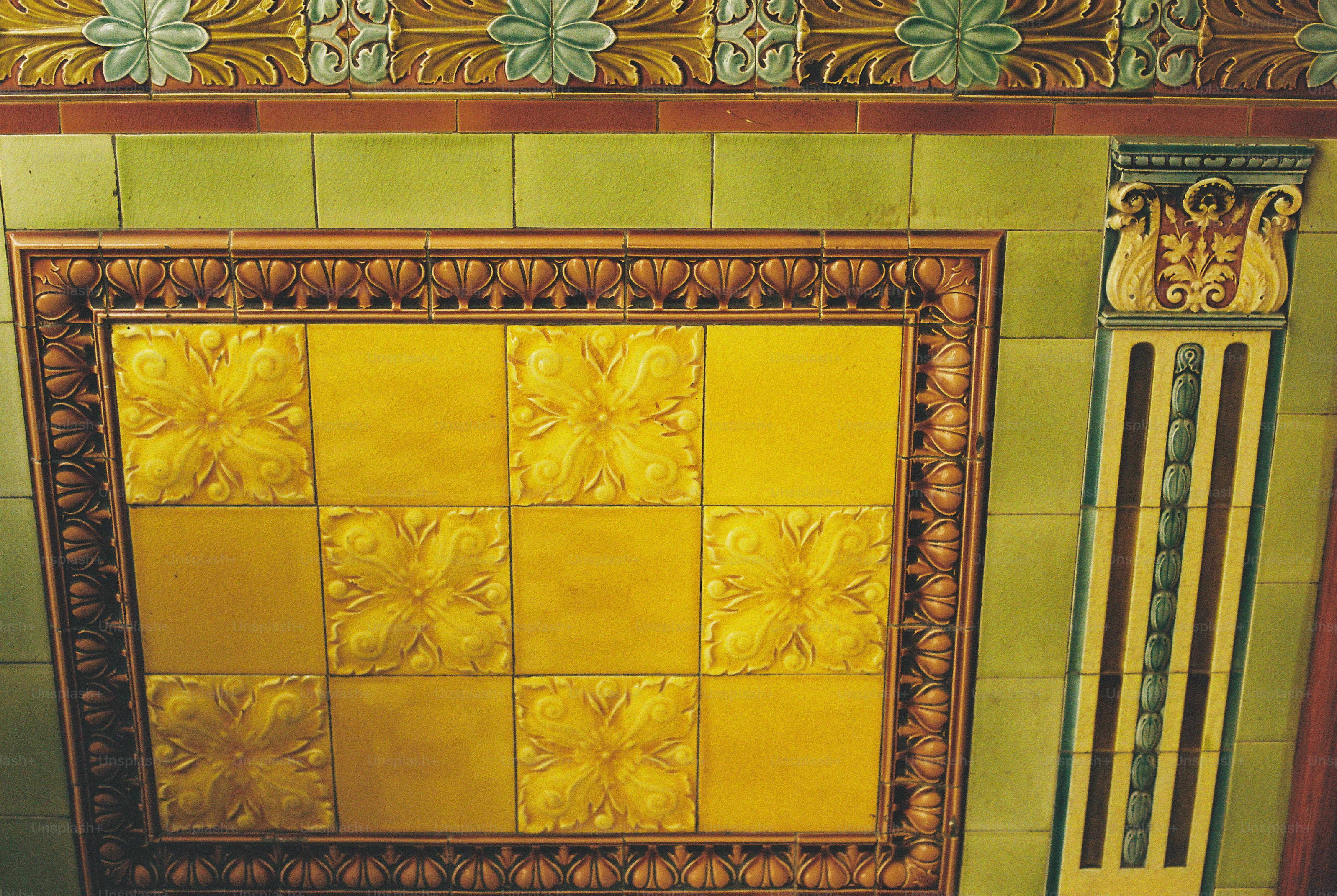 Decorative yellow and green ceramic tiles with floral relief patterns on a wall