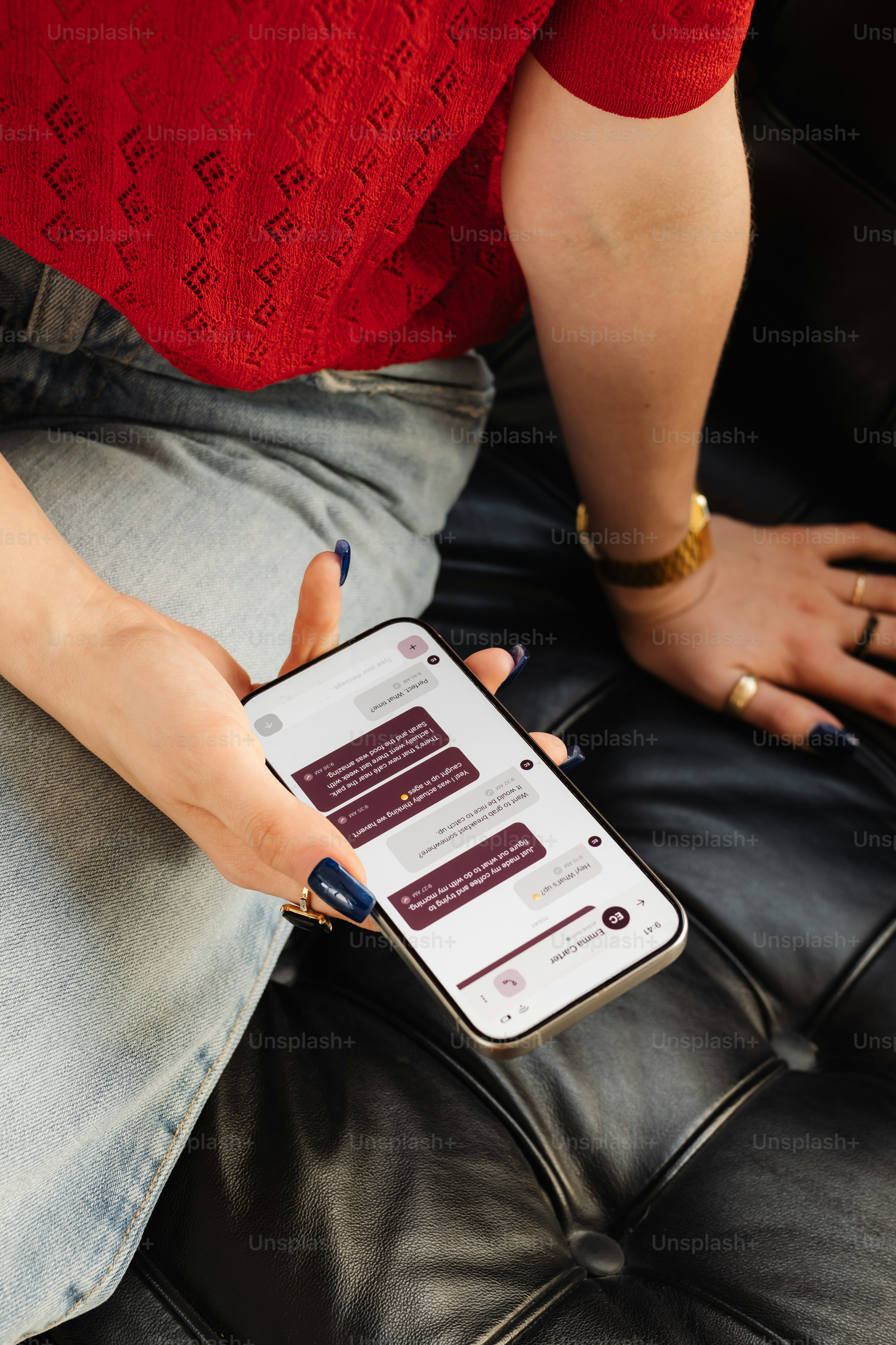 赤いトップスとジーンズを着た人がスマートフォンにメッセージを送っている