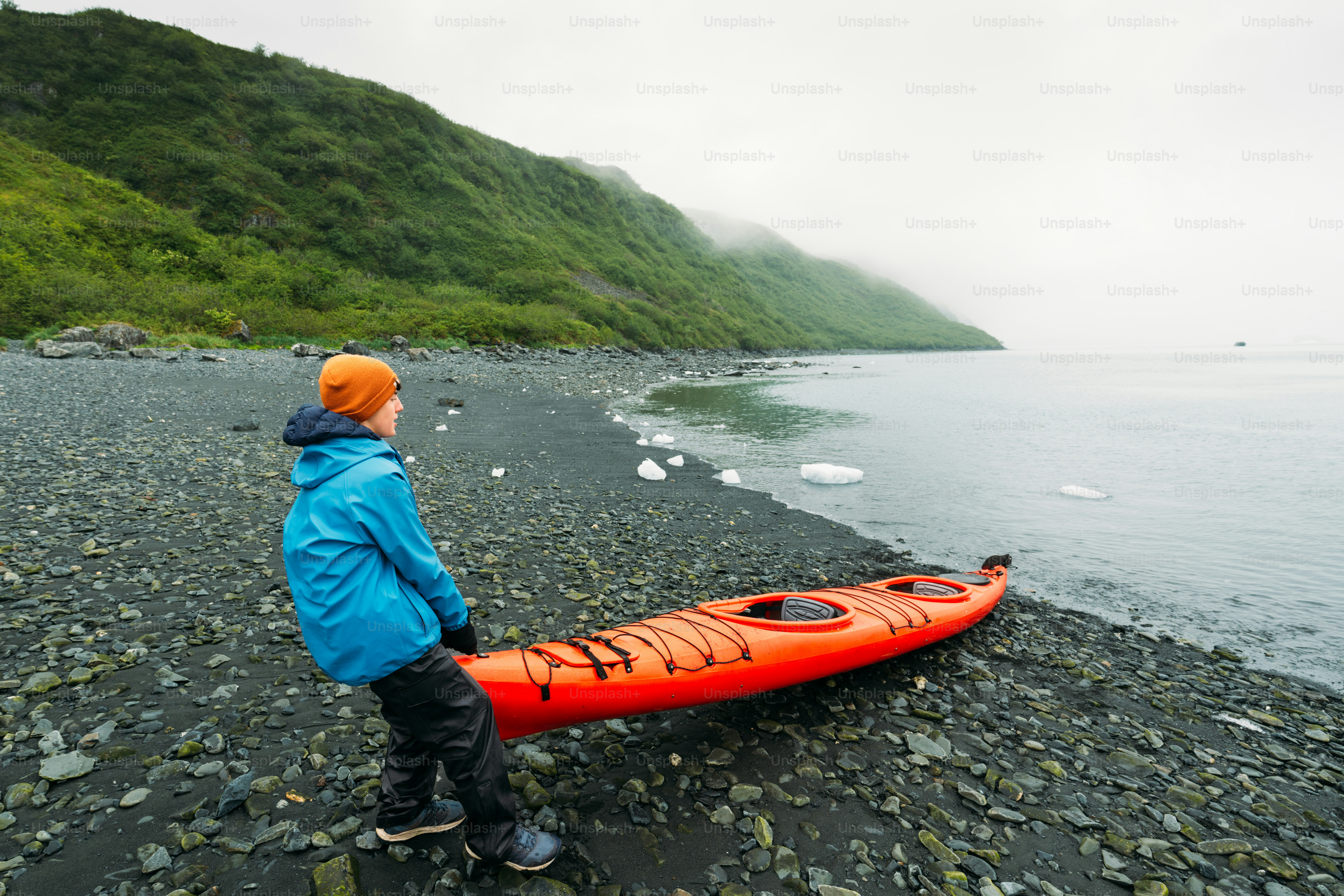 Chico adolescente preparando un kayak de mar para remar hasta el glaciar Aialik en Alaska