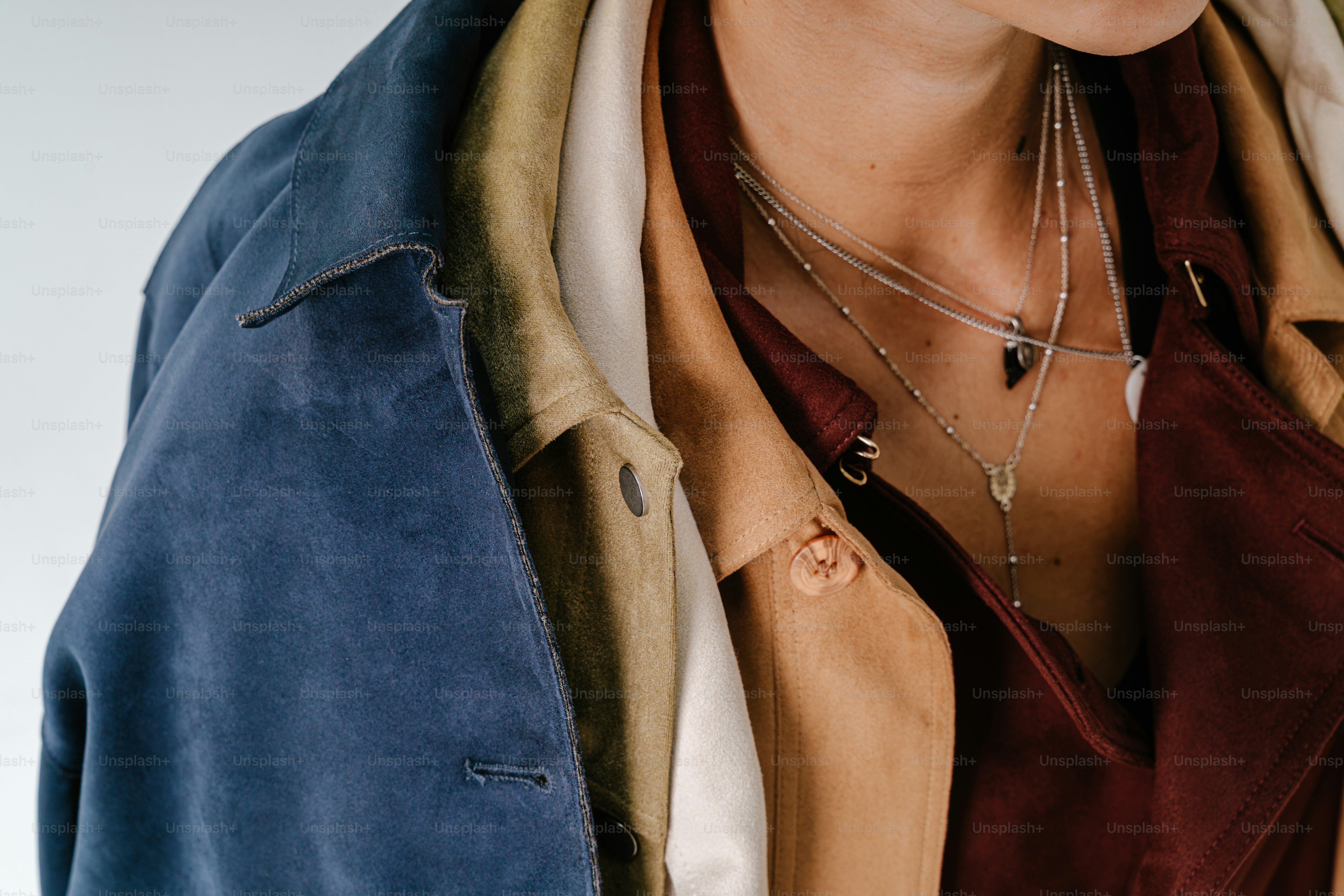 Une personne portant des vestes en daim superposées bleu, olive, beige et bordeaux