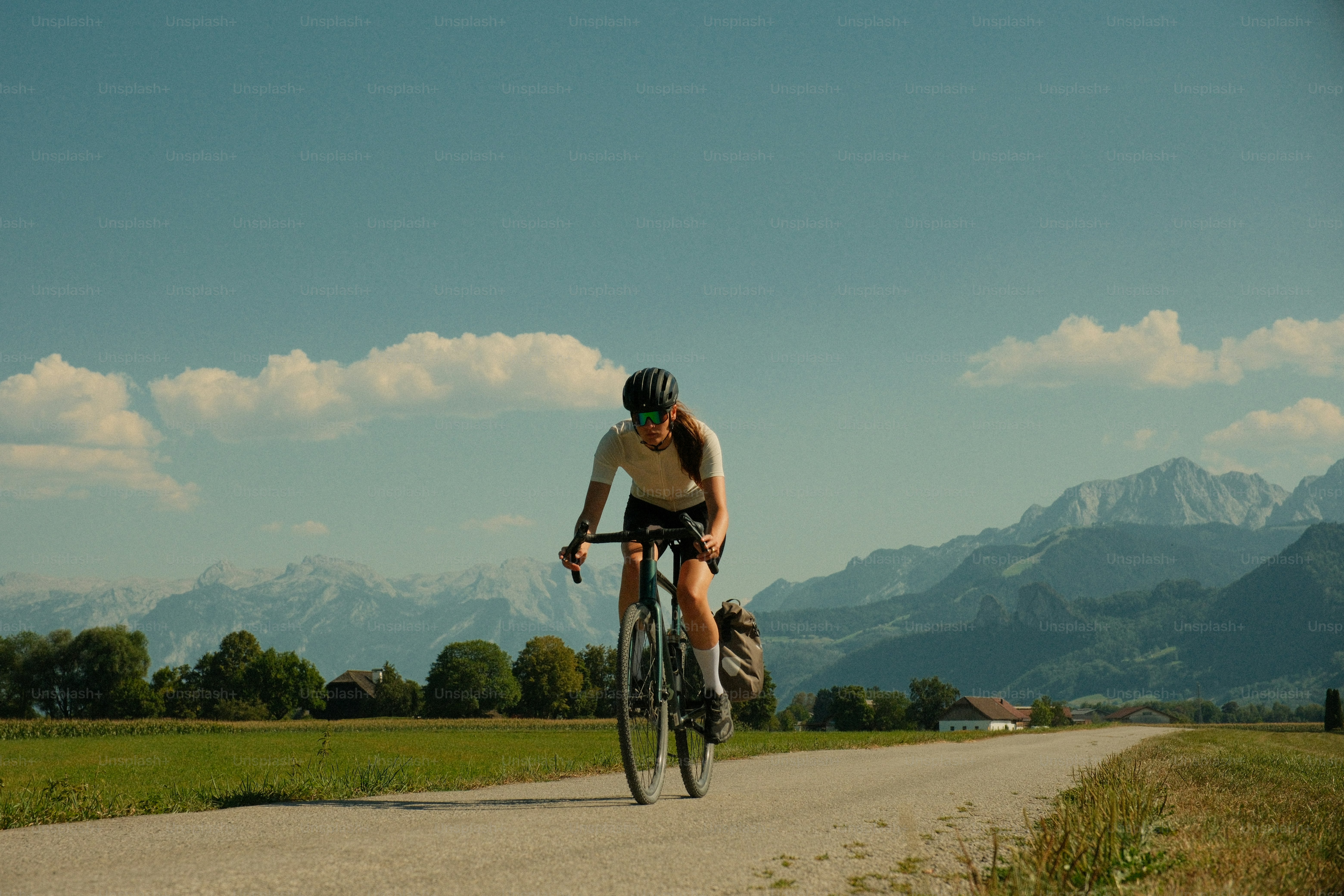Un ciclista che guida una gravel bike su una strada rurale con vista sulle montagne