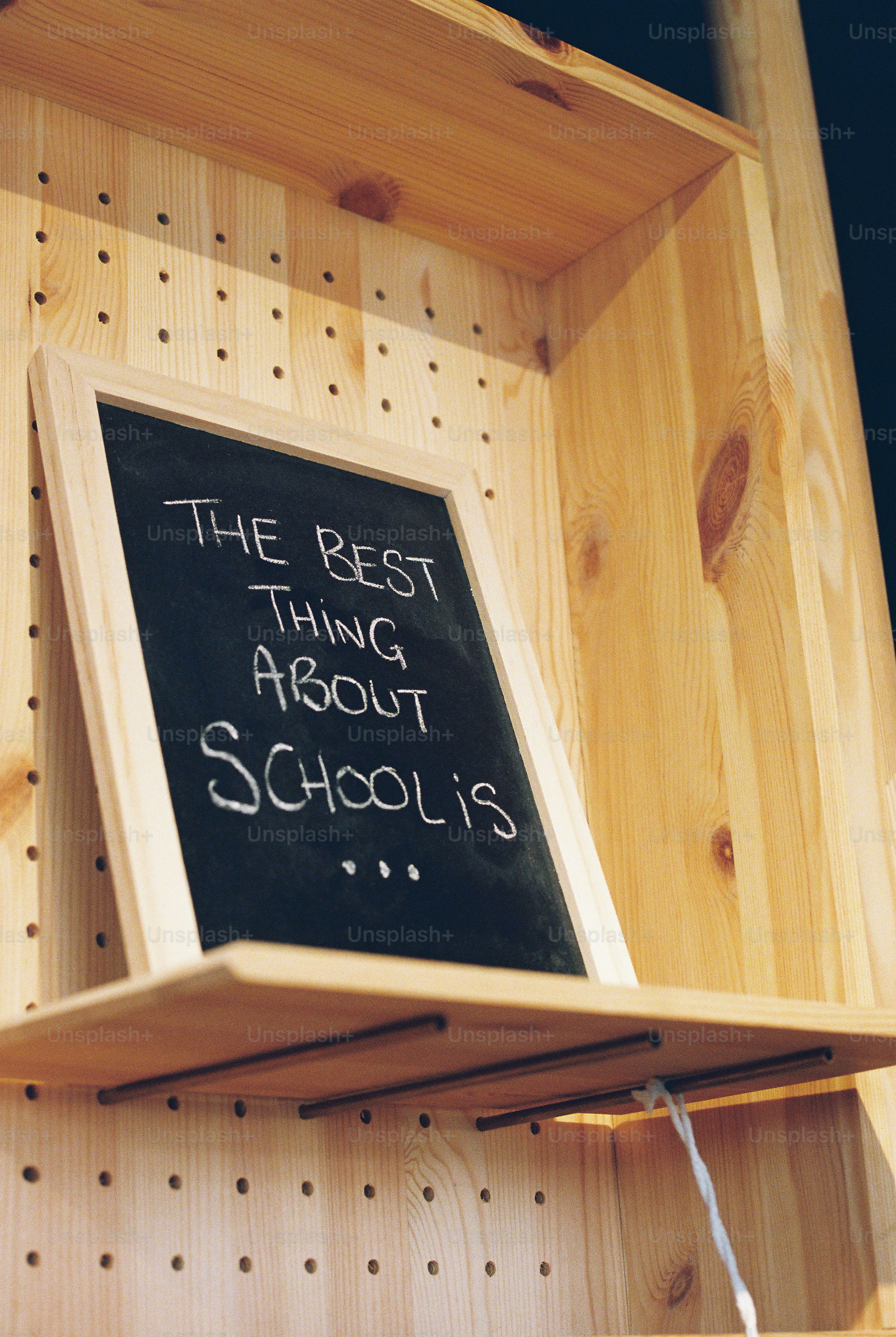 A framed chalkboard reading "THE BEST THING ABOUT SCHOOL IS..." on a wooden shelf