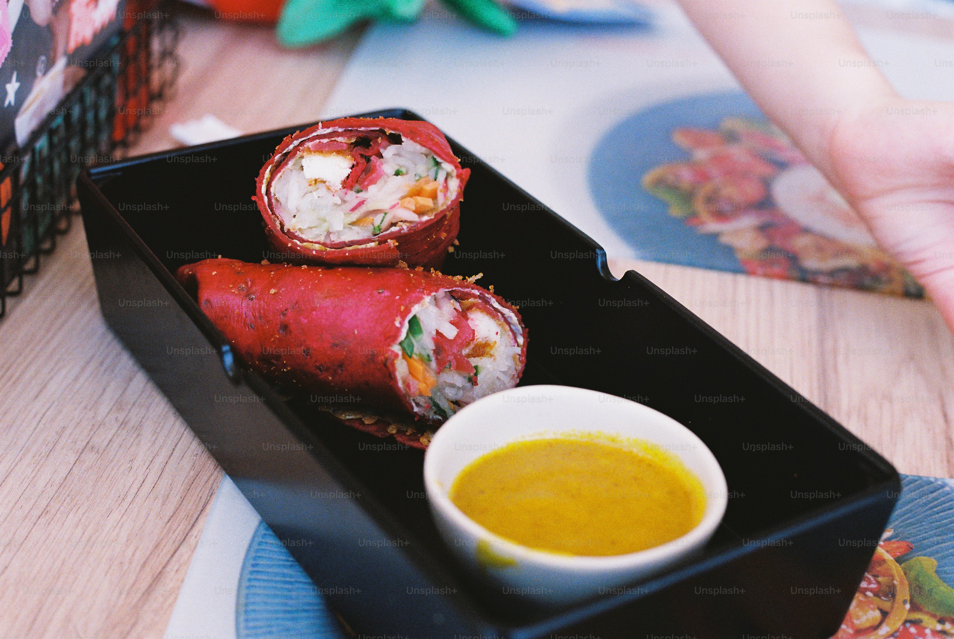 Two red vegetable wraps with a small bowl of yellow dipping sauce