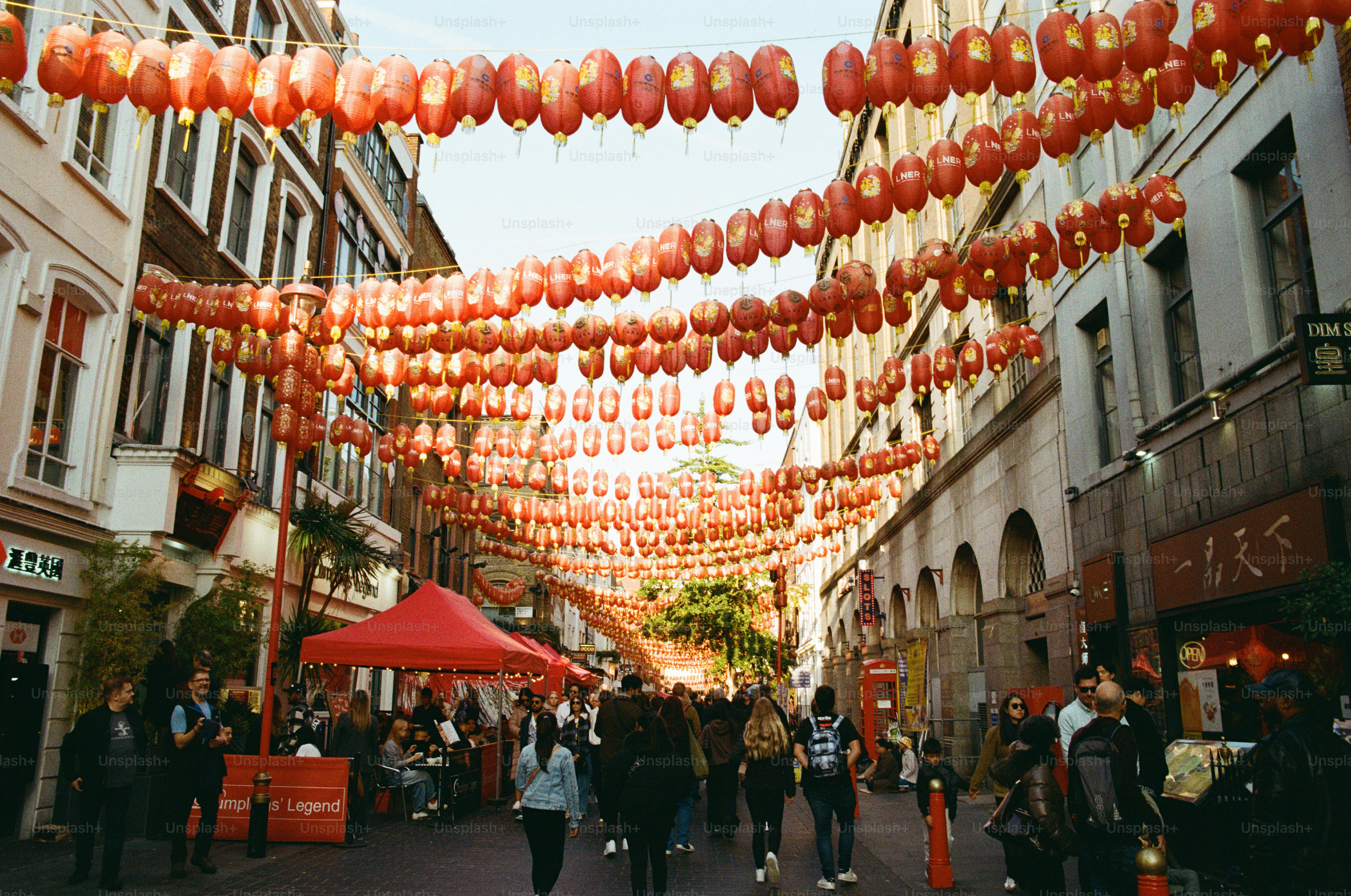 A crowd of people walking under rows of red lanterns in Chinatown, London