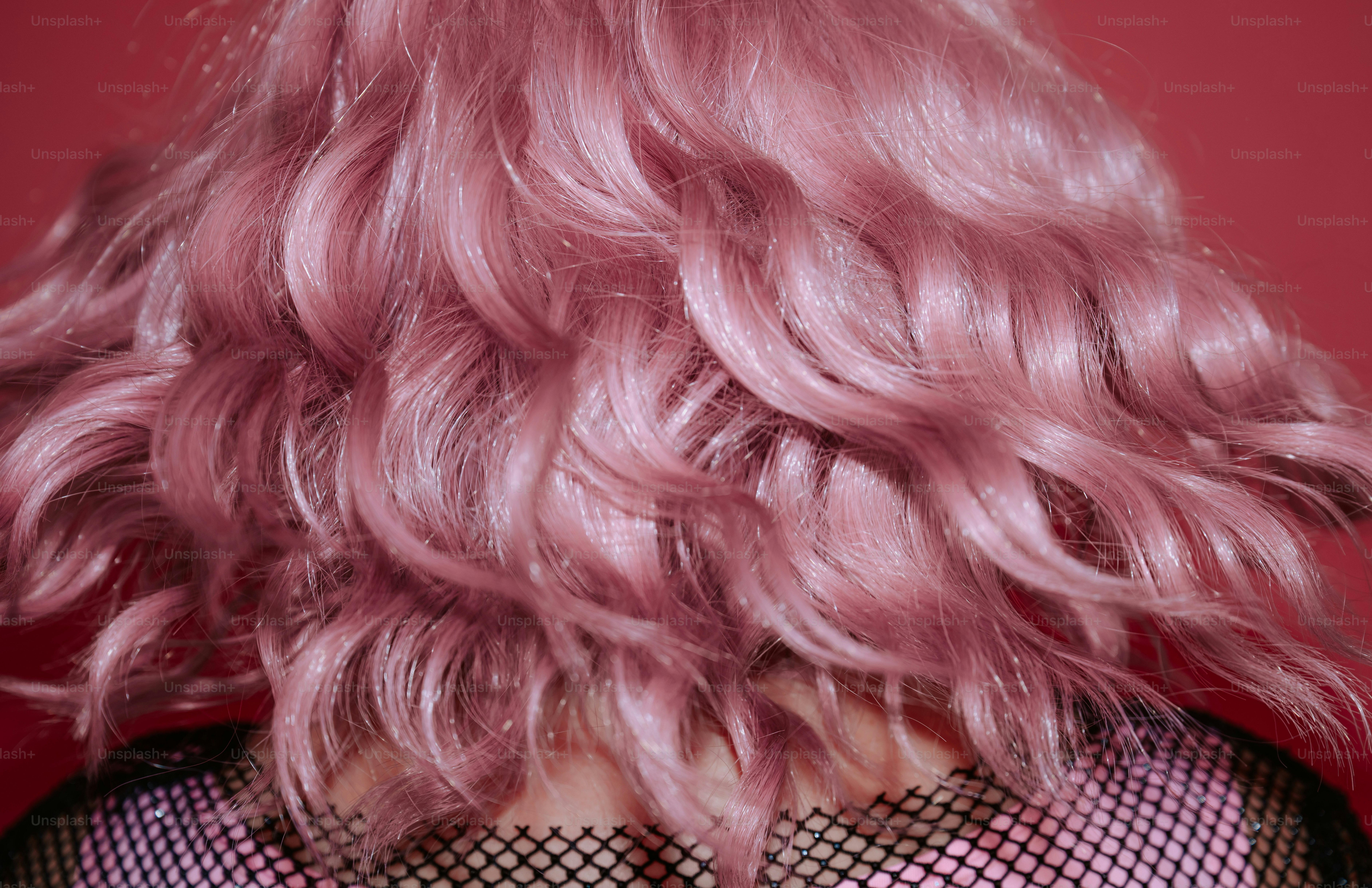 Wavy pastel pink hair seen from behind against a matching pink background