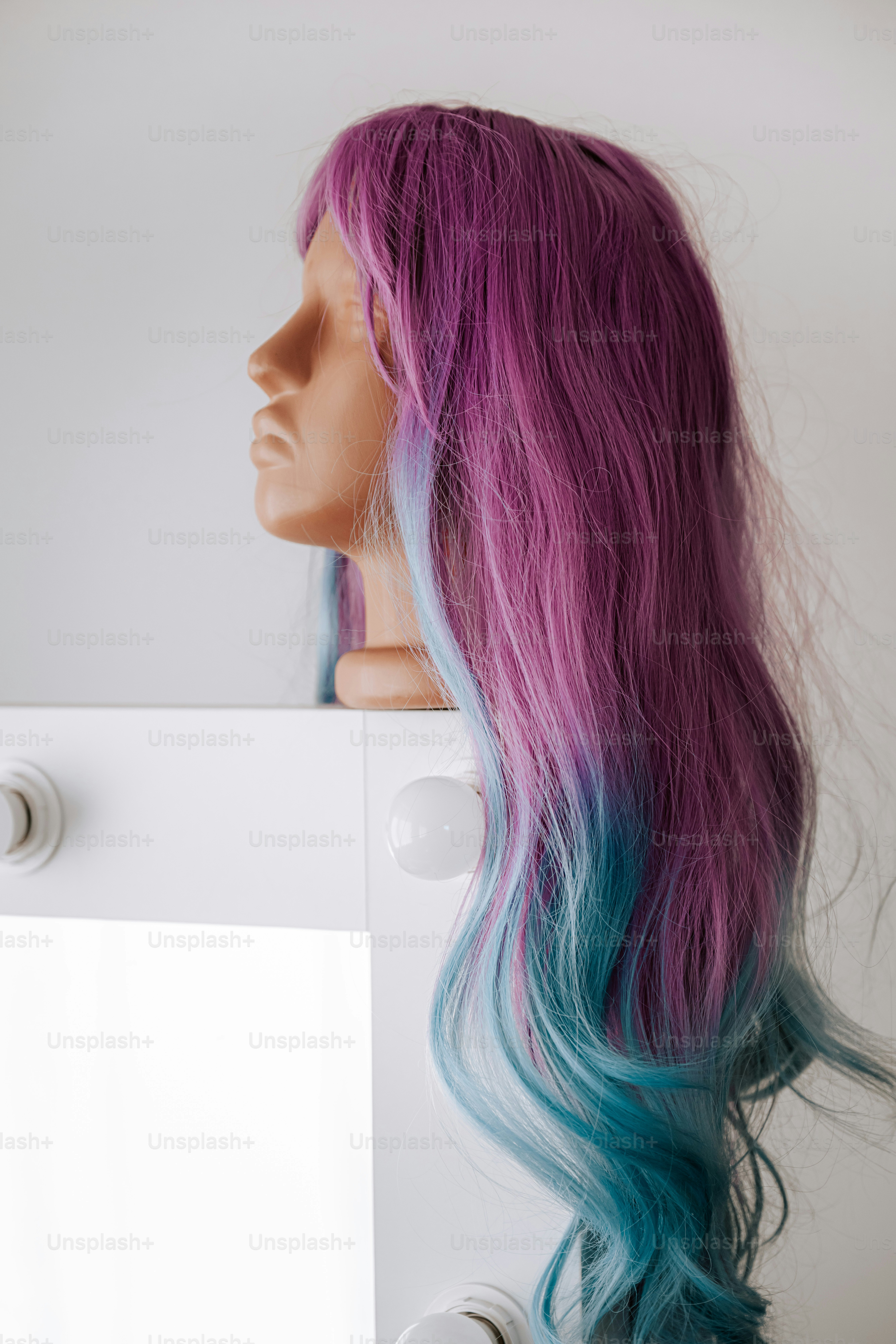 A mannequin head wearing a long wig with purple and blue ombre hair