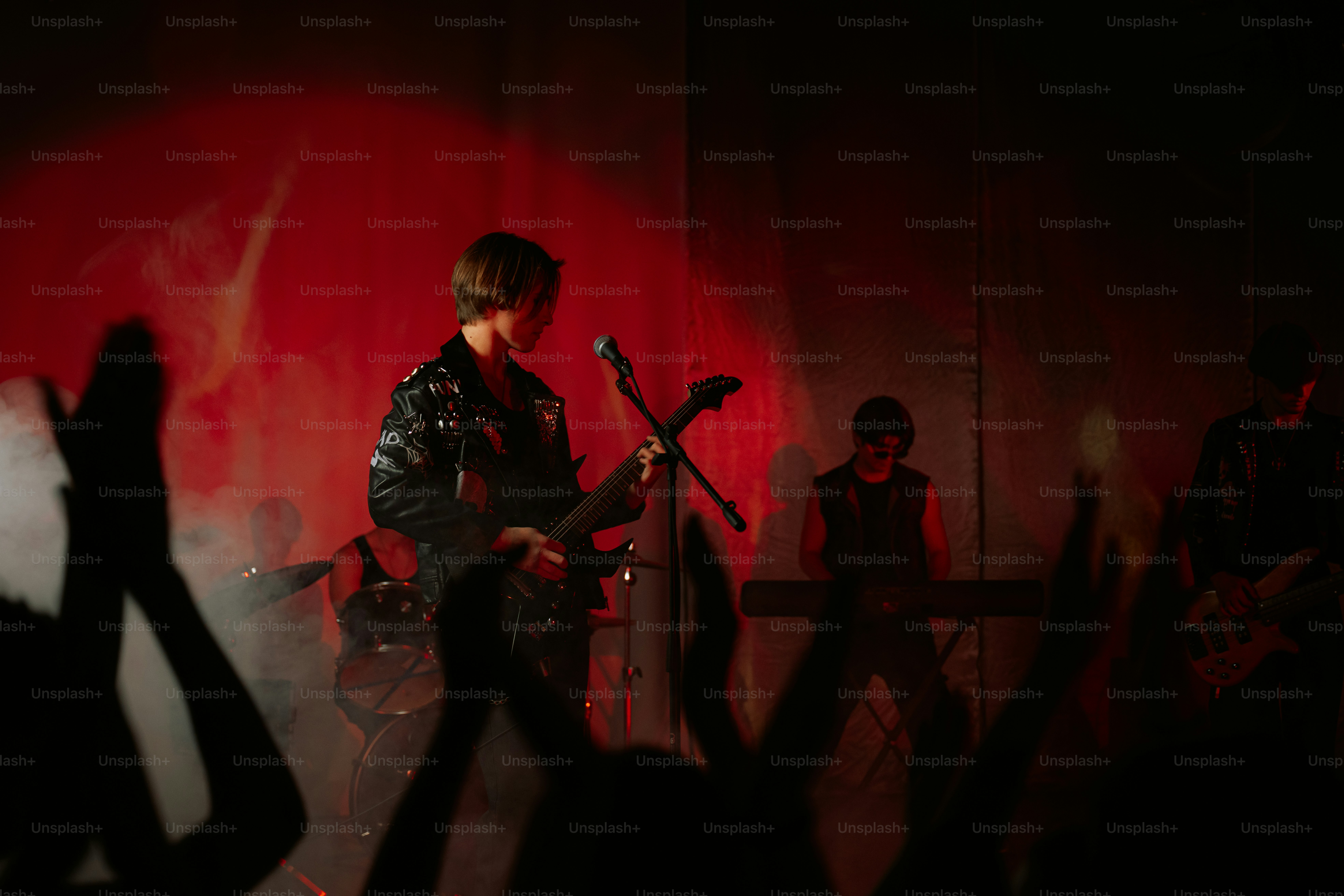 A band performing on a stage bathed in red light with a cheering crowd